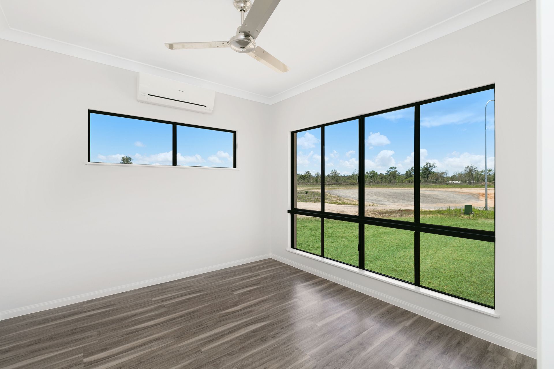 An Empty Bedroom With White Walls, Dark Wood-look Flooring — Ashlee Jones Homes in Gordonvale, QLD