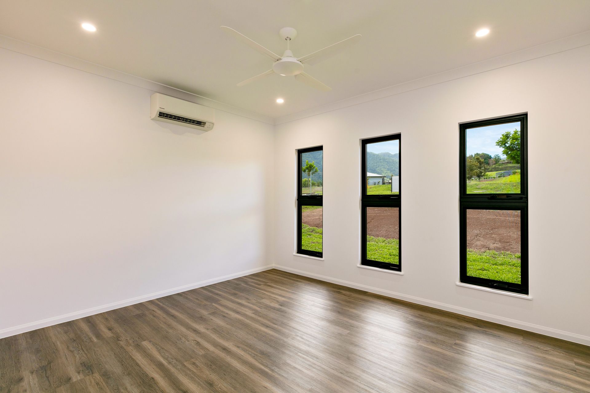 Empty Room With White Walls, Wood-look Flooring, a Ceiling Fan — Ashlee Jones Homes in Gordonvale, QLD