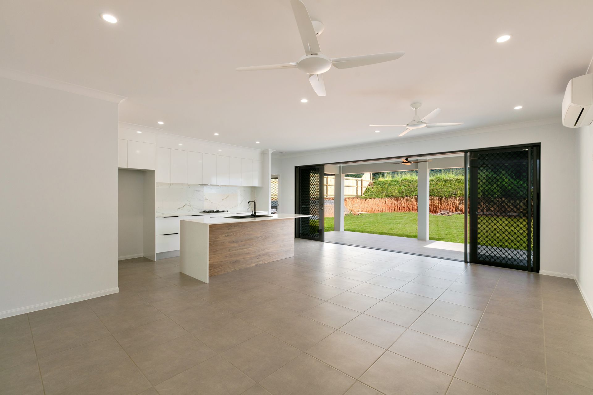 Modern Open-plan Kitchen and Living Area With White Cabinets — Ashlee Jones Homes in Gordonvale, QLD