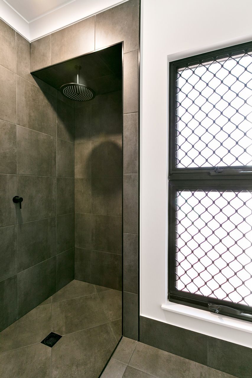 A Walk-in Shower With Dark Gray Stone Tiles — Ashlee Jones Homes in Gordonvale, QLD