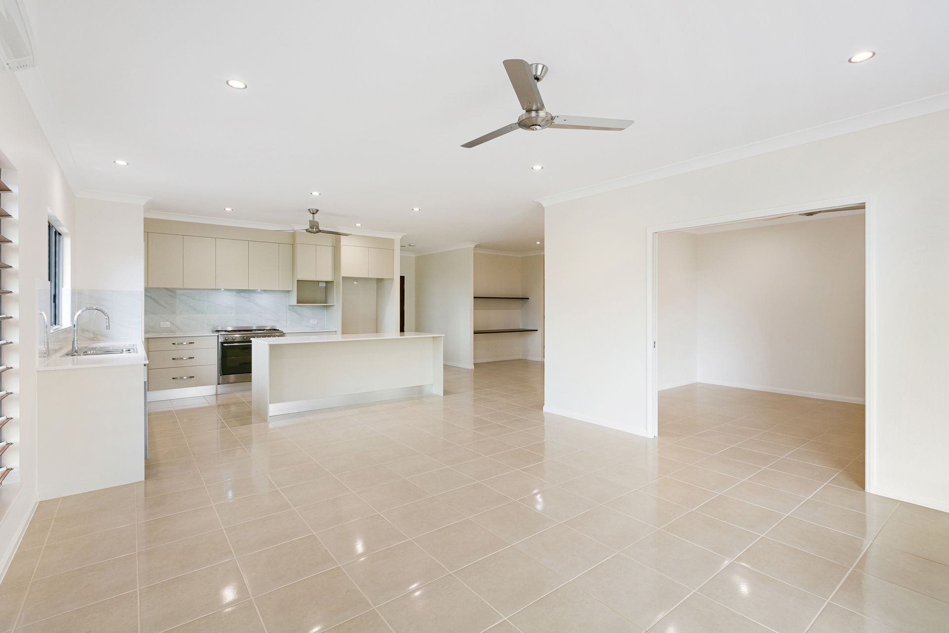 Open-plan Kitchen and Living Space With Light Tile Flooring — Ashlee Jones Homes in Gordonvale, QLD
