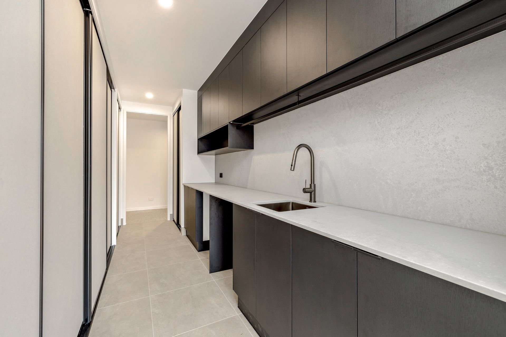 A Modern Kitchen Galley With Dark Charcoal Cabinets — Ashlee Jones Homes in Gordonvale, QLD