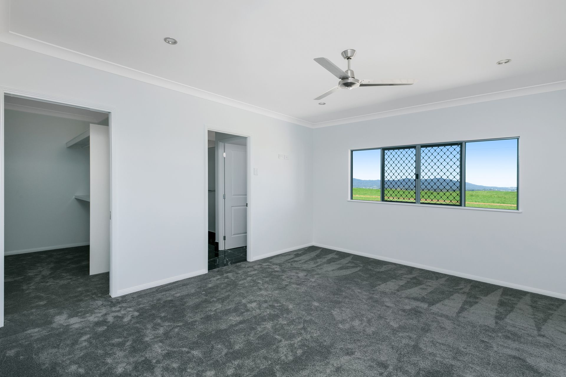 An Empty Bedroom With White Walls, Dark Gray Carpet — Ashlee Jones Homes in Gordonvale, QLD