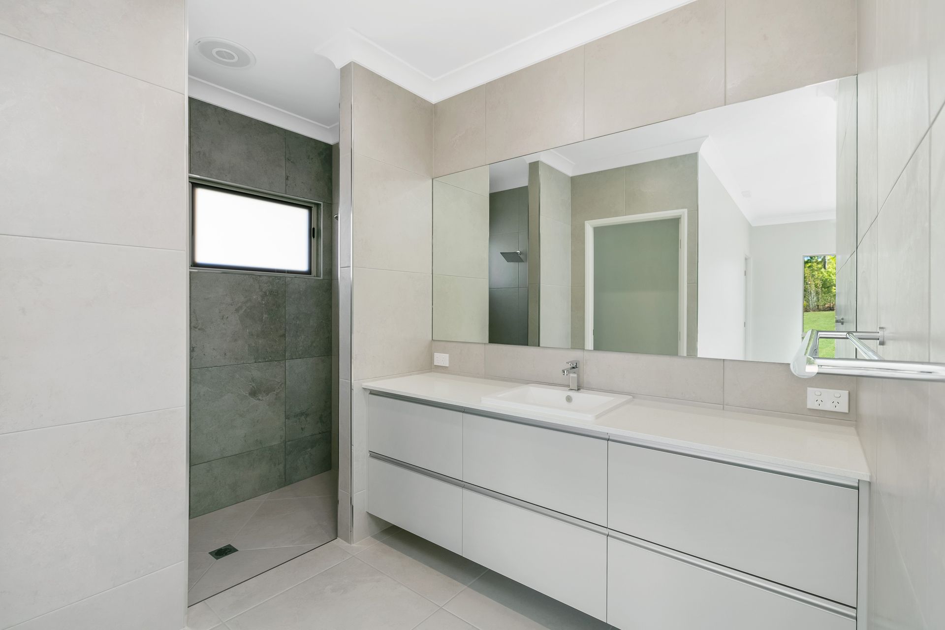A Modern Bathroom Featuring a White Vanity With a Mirror — Ashlee Jones Homes in Gordonvale, QLD