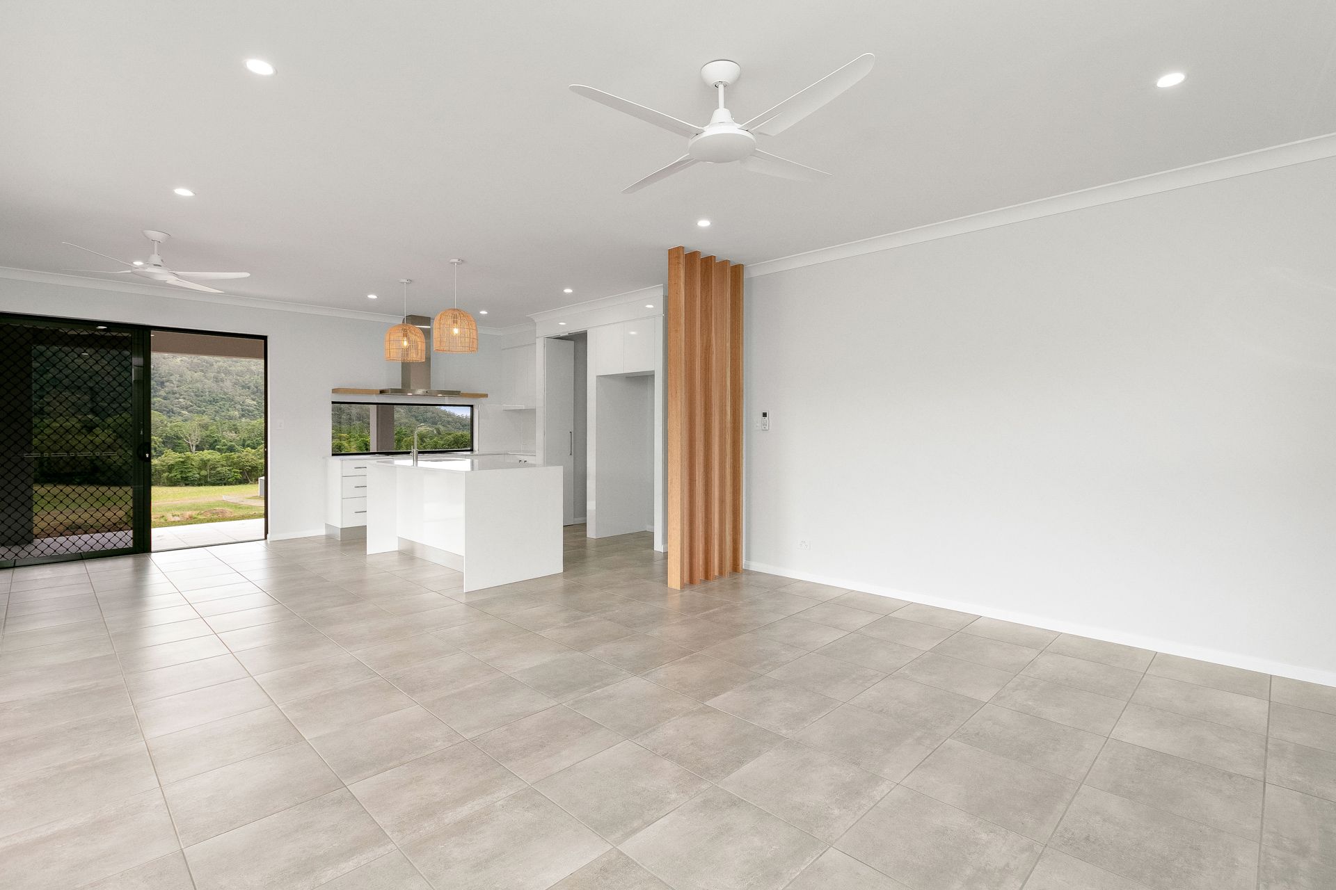 A Bright, Open-plan Living and Kitchen Area With Light Grey Tile Floors — Ashlee Jones Homes in Gordonvale, QLD