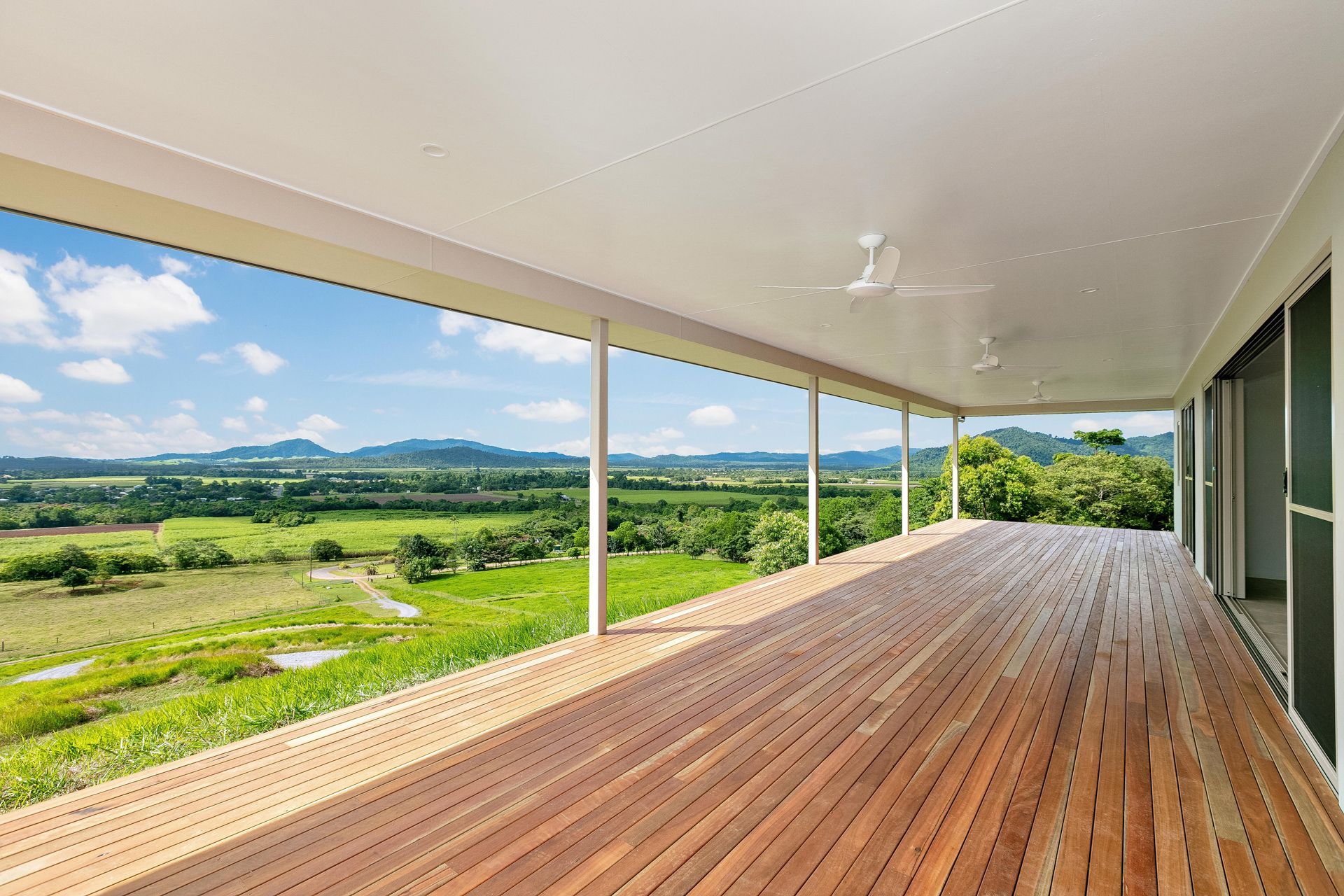 A Wide, Covered Wooden Deck Overlooks a Vast Green Landscape — Ashlee Jones Homes in Gordonvale, QLD