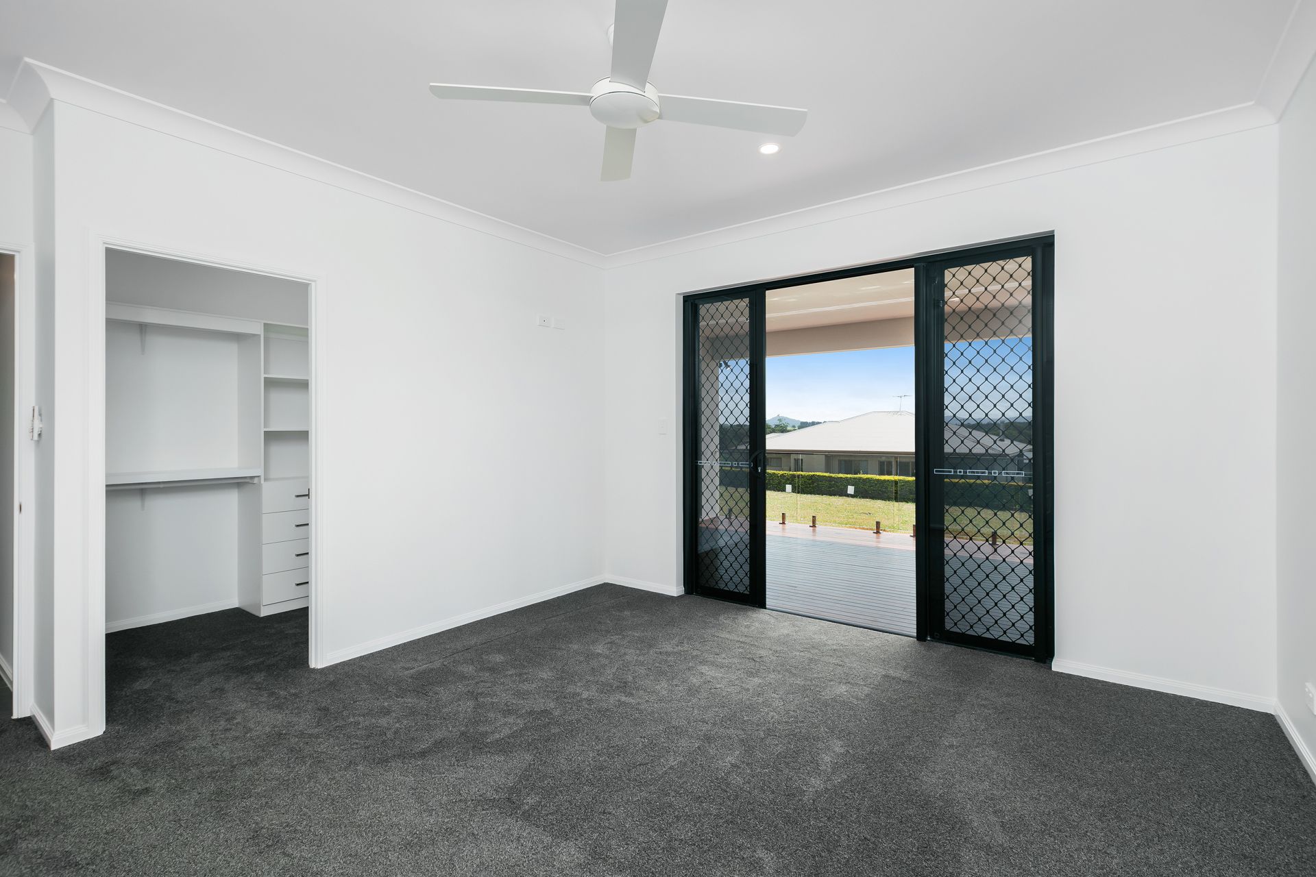 An Empty Bedroom With White Walls, Gray Carpet — Ashlee Jones Homes in Gordonvale, QLD