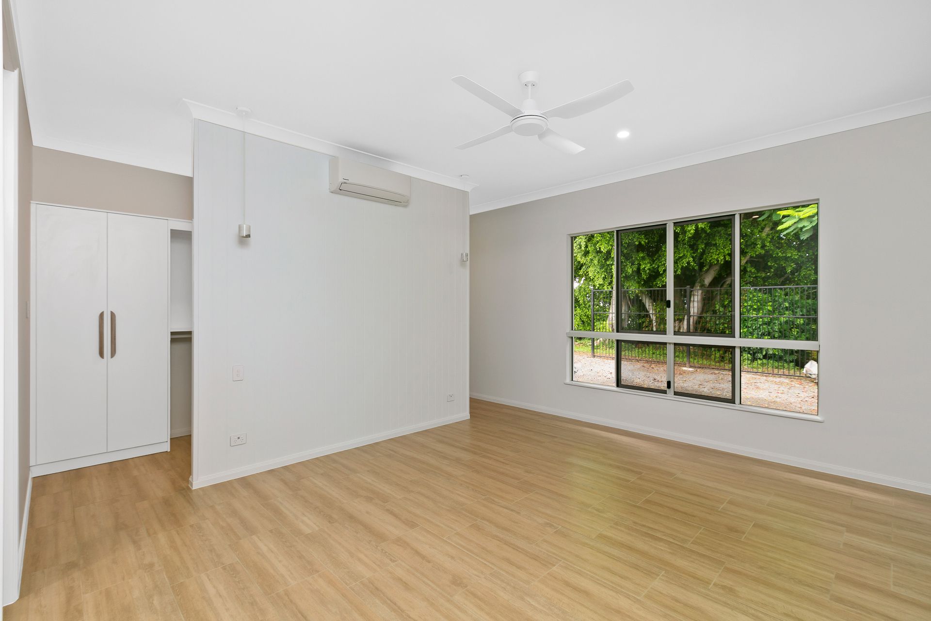 A Bright, Empty Bedroom With Light Wood Flooring — Ashlee Jones Homes in Gordonvale, QLD