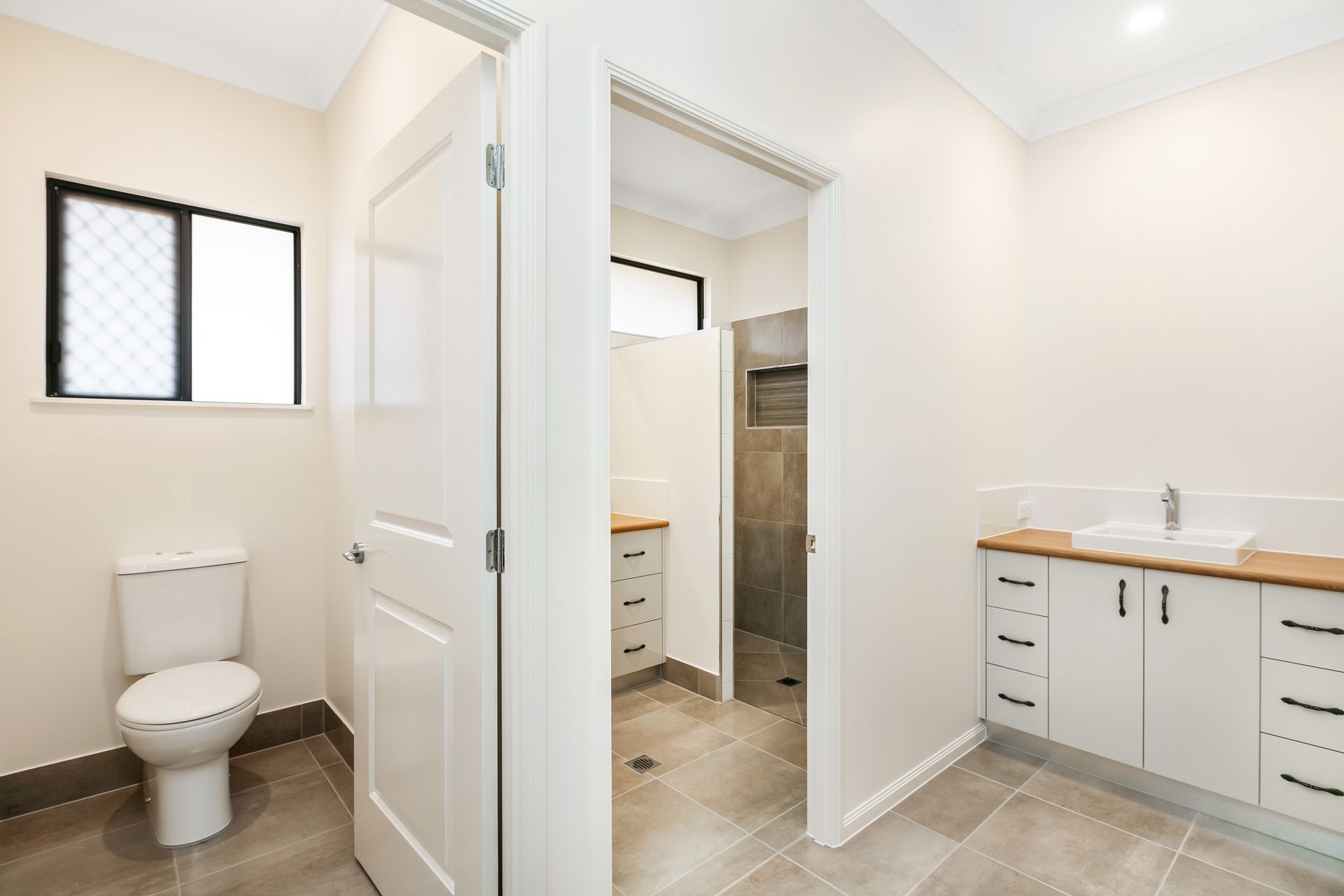 A Neutral-toned Bathroom With a Toilet, a Vanity With Double Sinks — Ashlee Jones Homes in Gordonvale, QLD