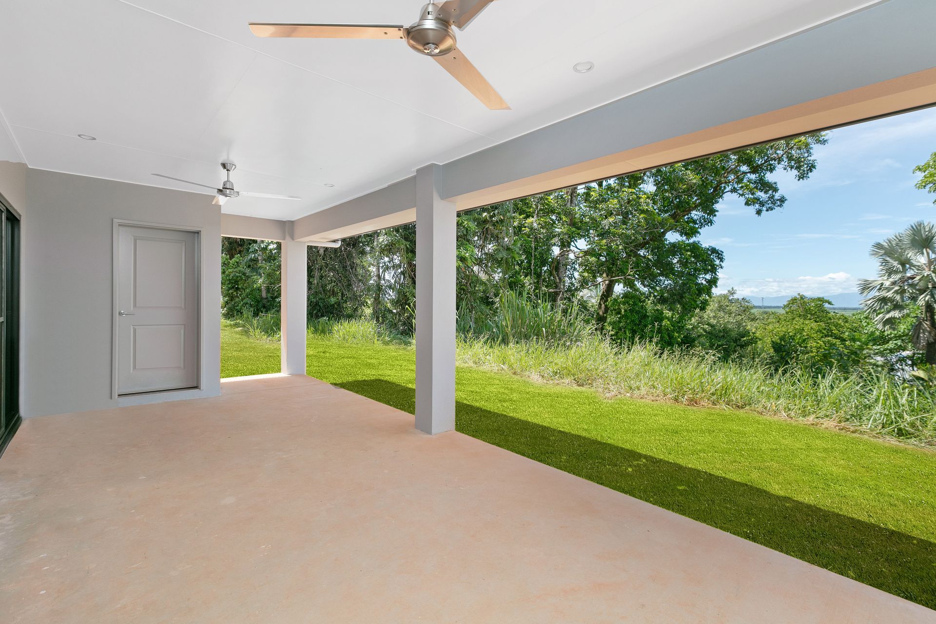 A Spacious Covered Patio With Ceiling Fans, Concrete Flooring — Ashlee Jones Homes in Gordonvale, QLD