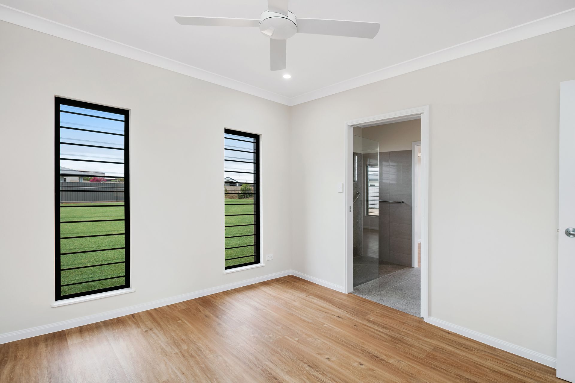 A Bright, Empty Bedroom With Light Wood Flooring — Ashlee Jones Homes in Gordonvale, QLD