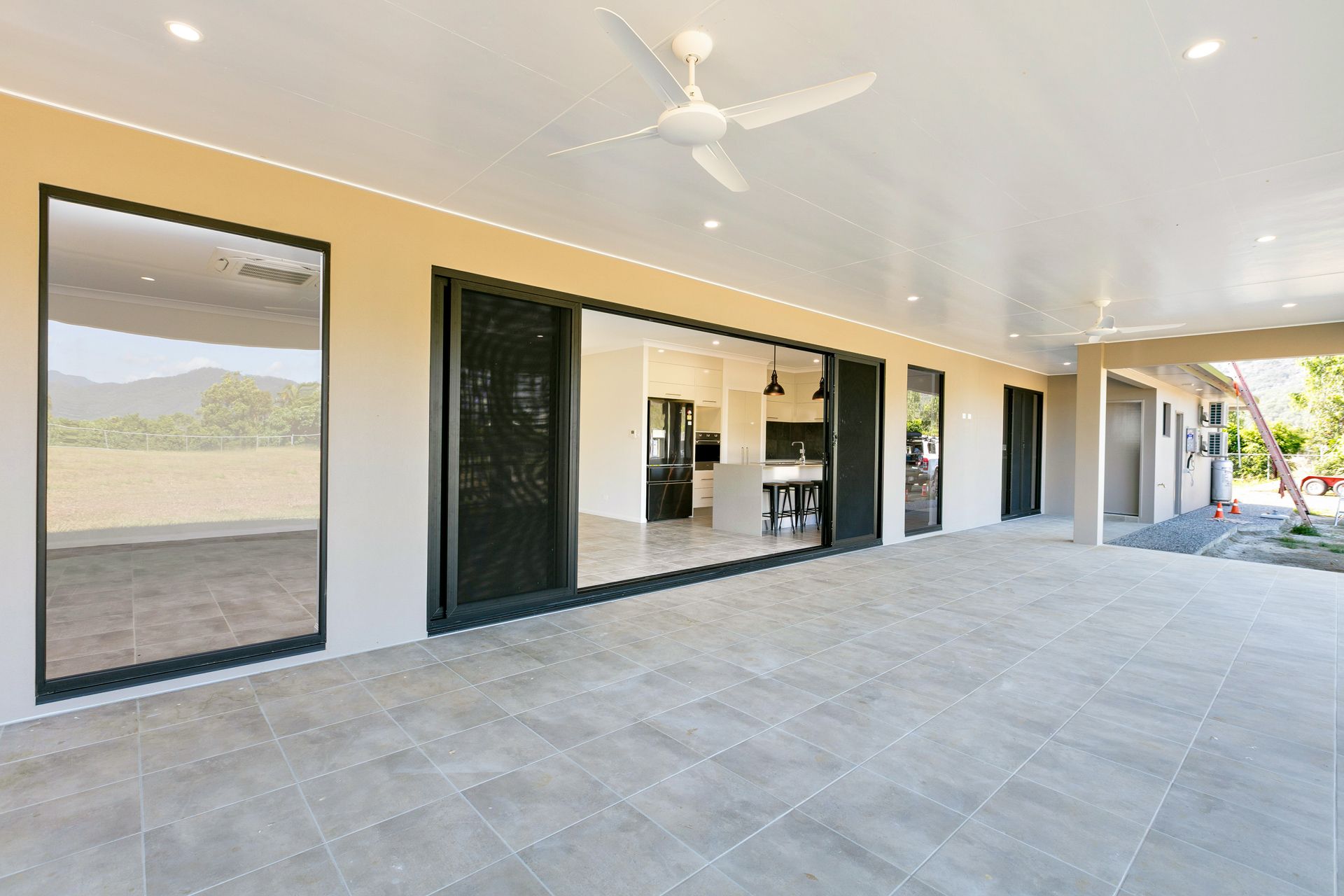 A Spacious, Covered Outdoor Patio Featuring Light Gray Tiled Floors — Ashlee Jones Homes in Gordonvale, QLD