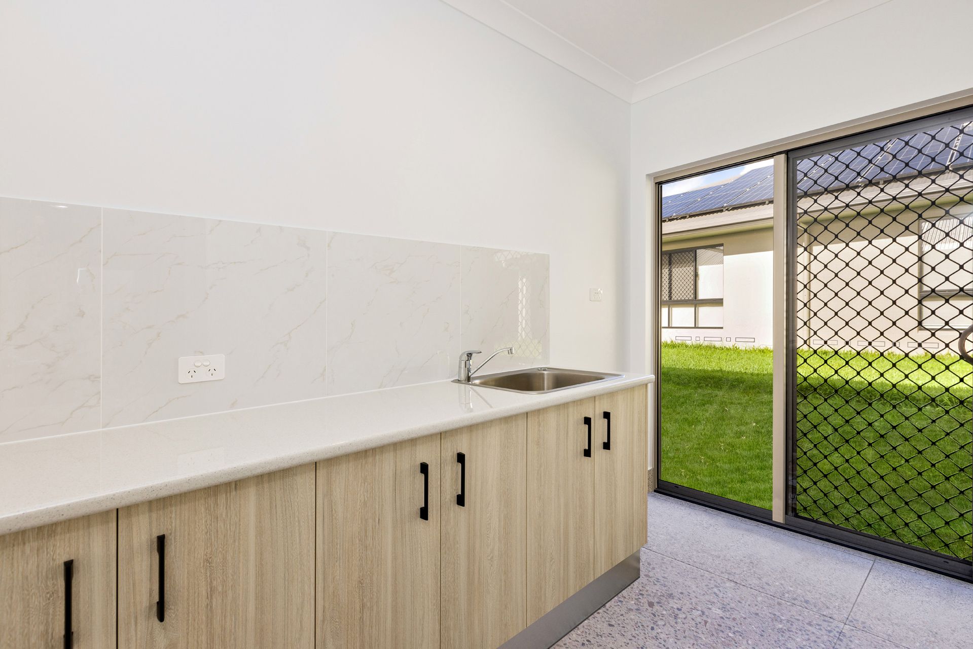 A Bright Kitchen or Laundry Space Featuring Light Wood Cabinets — Ashlee Jones Homes in Gordonvale, QLD