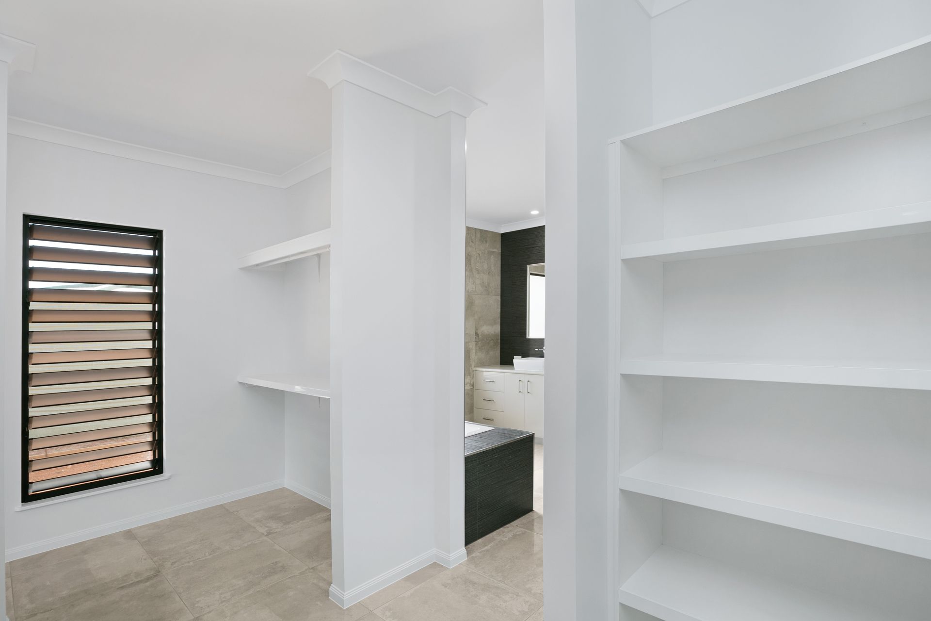 A Bright, White Walk-in Closet With Built-in Shelving Units — Ashlee Jones Homes in Gordonvale, QLD