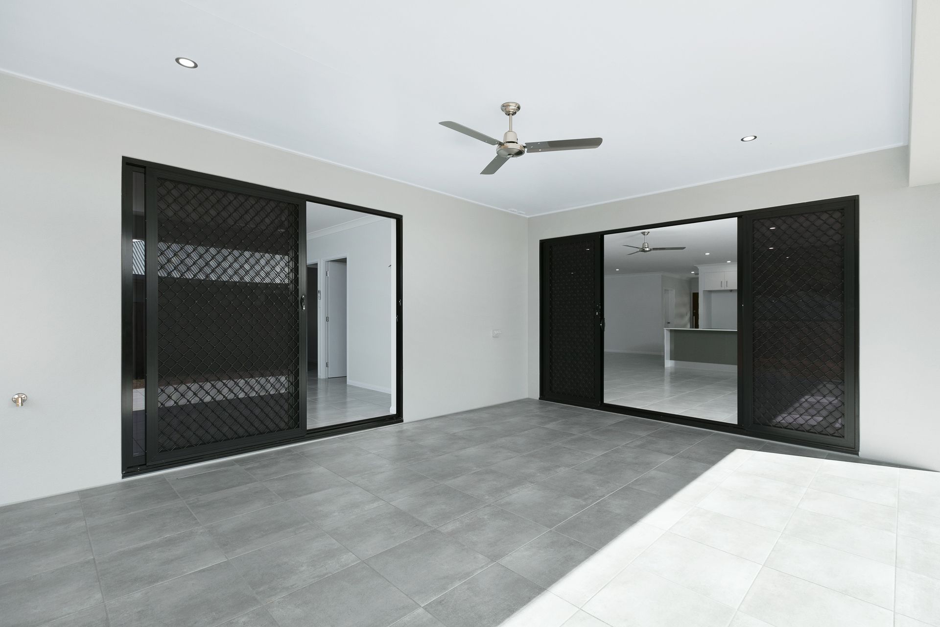 A Covered Patio With Light Grey Walls, Dark Tiled Floors — Ashlee Jones Homes in Gordonvale, QLD