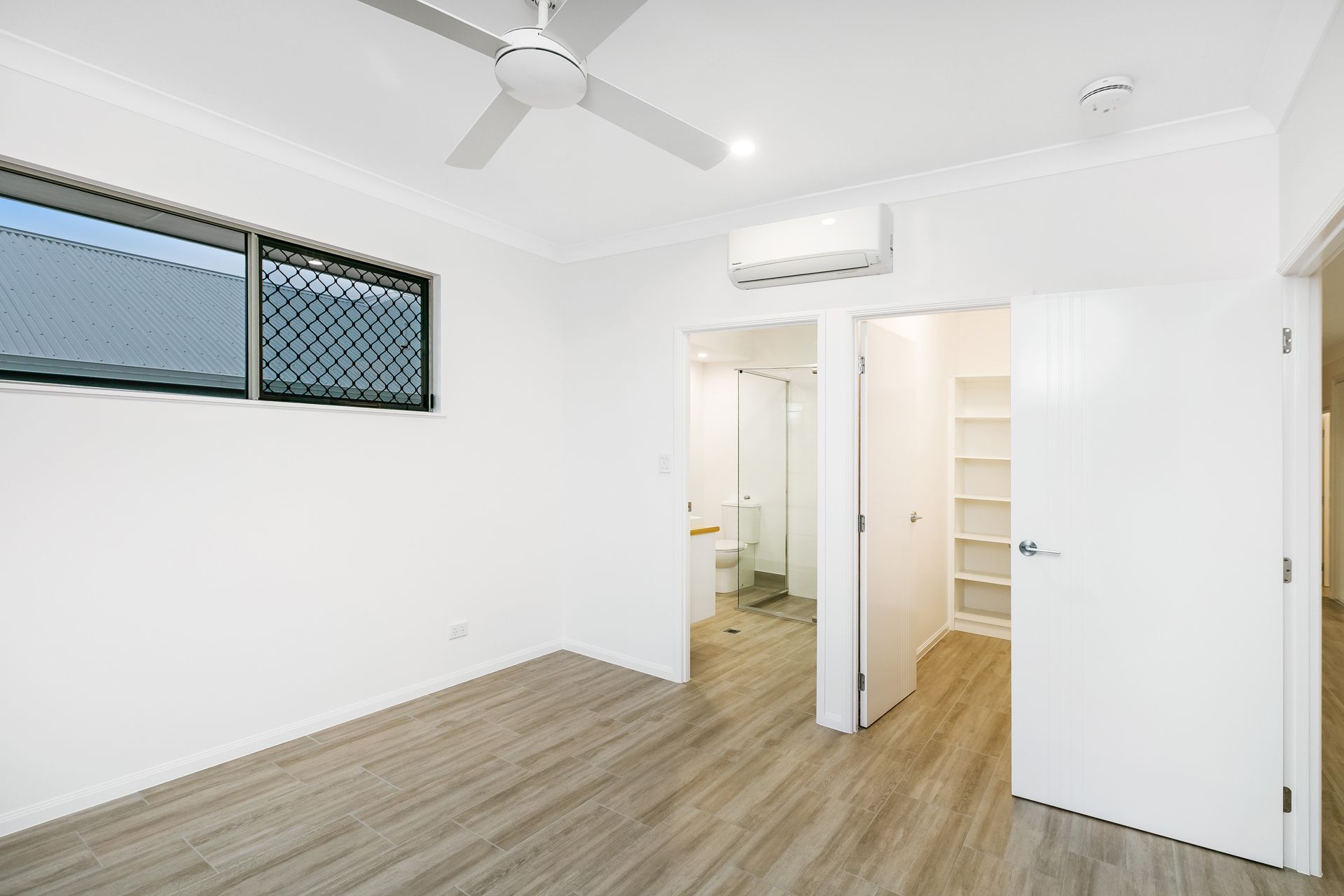 A Brightly Lit, Empty Bedroom With White Walls, Wood-look Flooring — Ashlee Jones Homes in Gordonvale, QLD