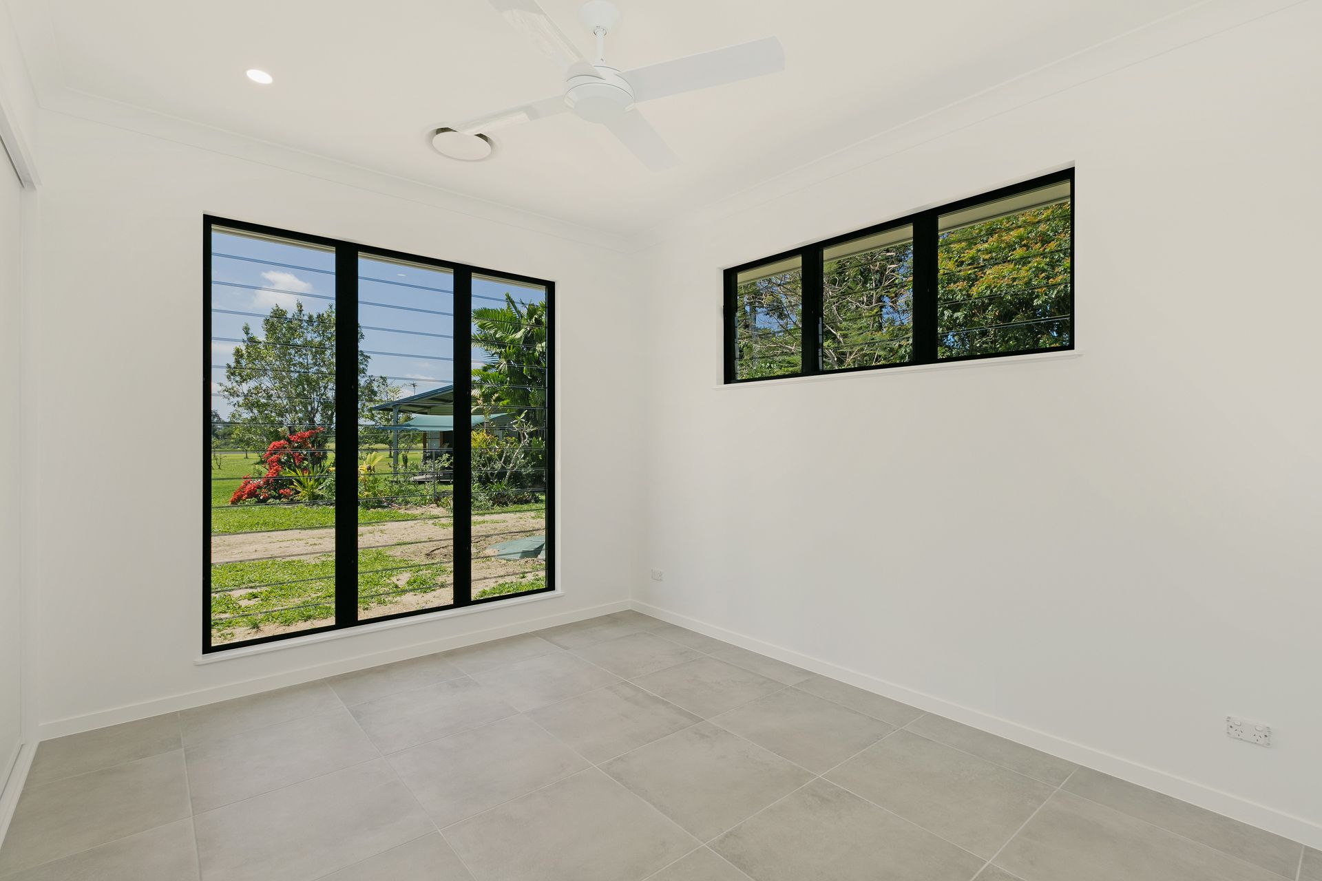 A Bright, Empty Room With White Walls, Grey Tile Flooring — Ashlee Jones Homes in Gordonvale, QLD