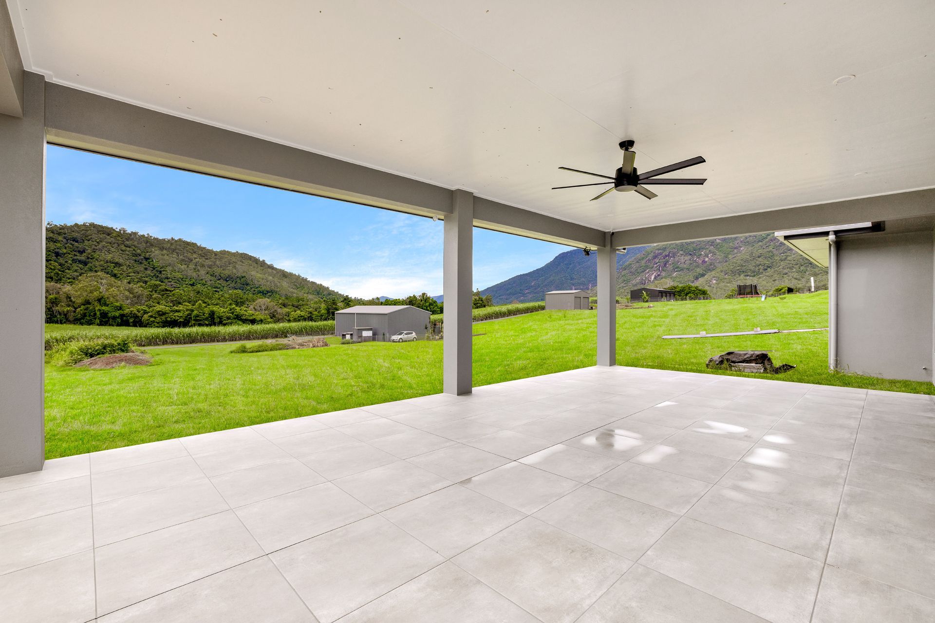 A Covered Patio With Light Grey Tiled Flooring — Ashlee Jones Homes in Gordonvale, QLD