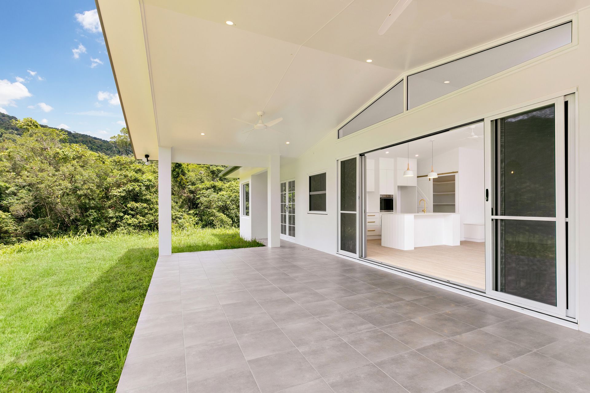 A Wide, Covered Patio With Light Grey Tiled Flooring — Ashlee Jones Homes in Gordonvale, QLD