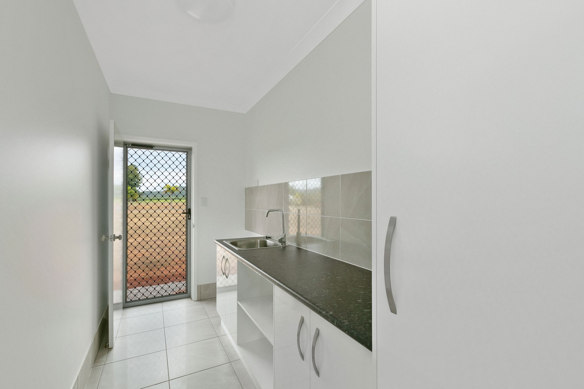 A Small, Bright Laundry Room With White Cabinets — Ashlee Jones Homes in Gordonvale, QLD