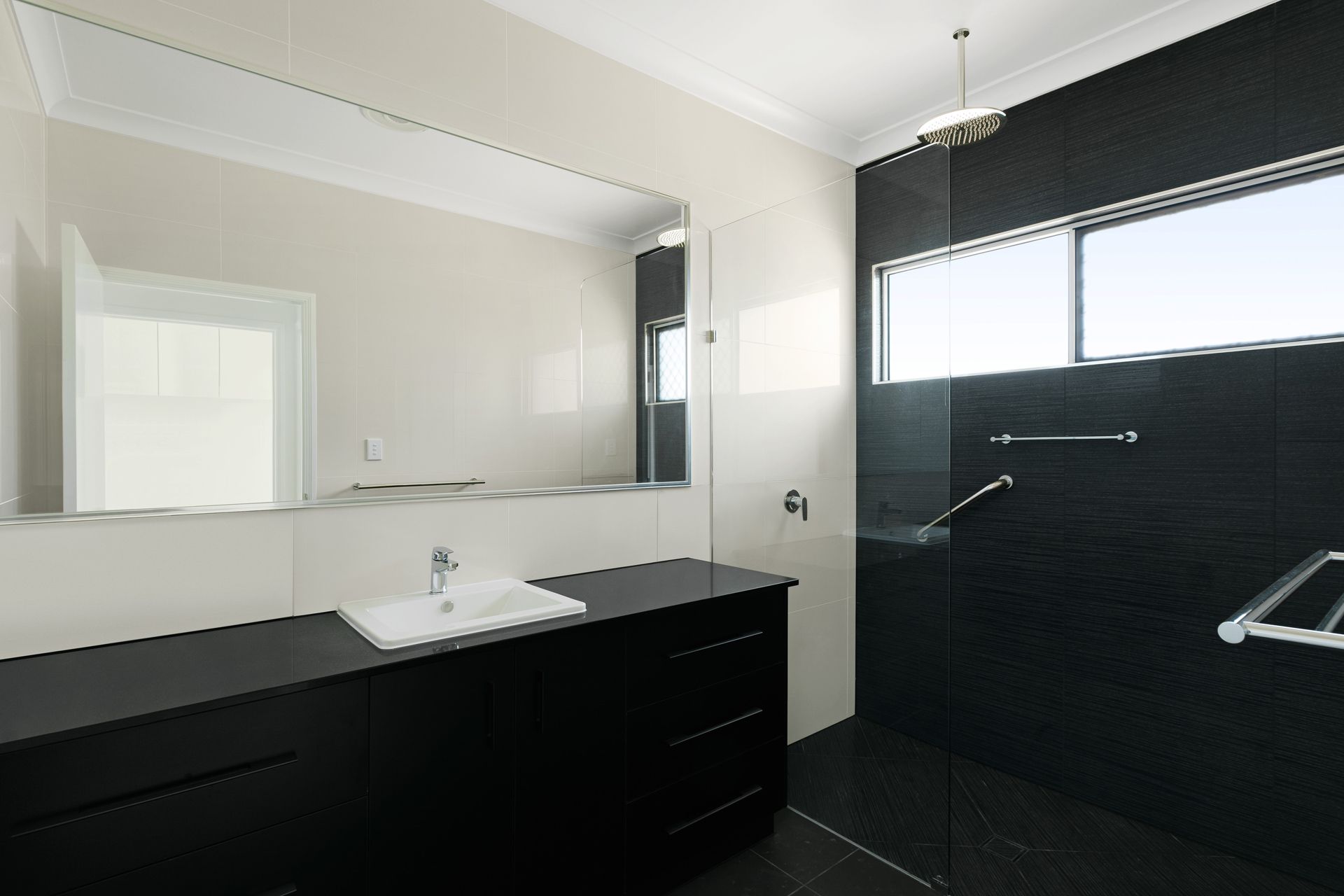 Modern Bathroom Featuring a Black Vanity With a White Sink — Ashlee Jones Homes in Gordonvale, QLD
