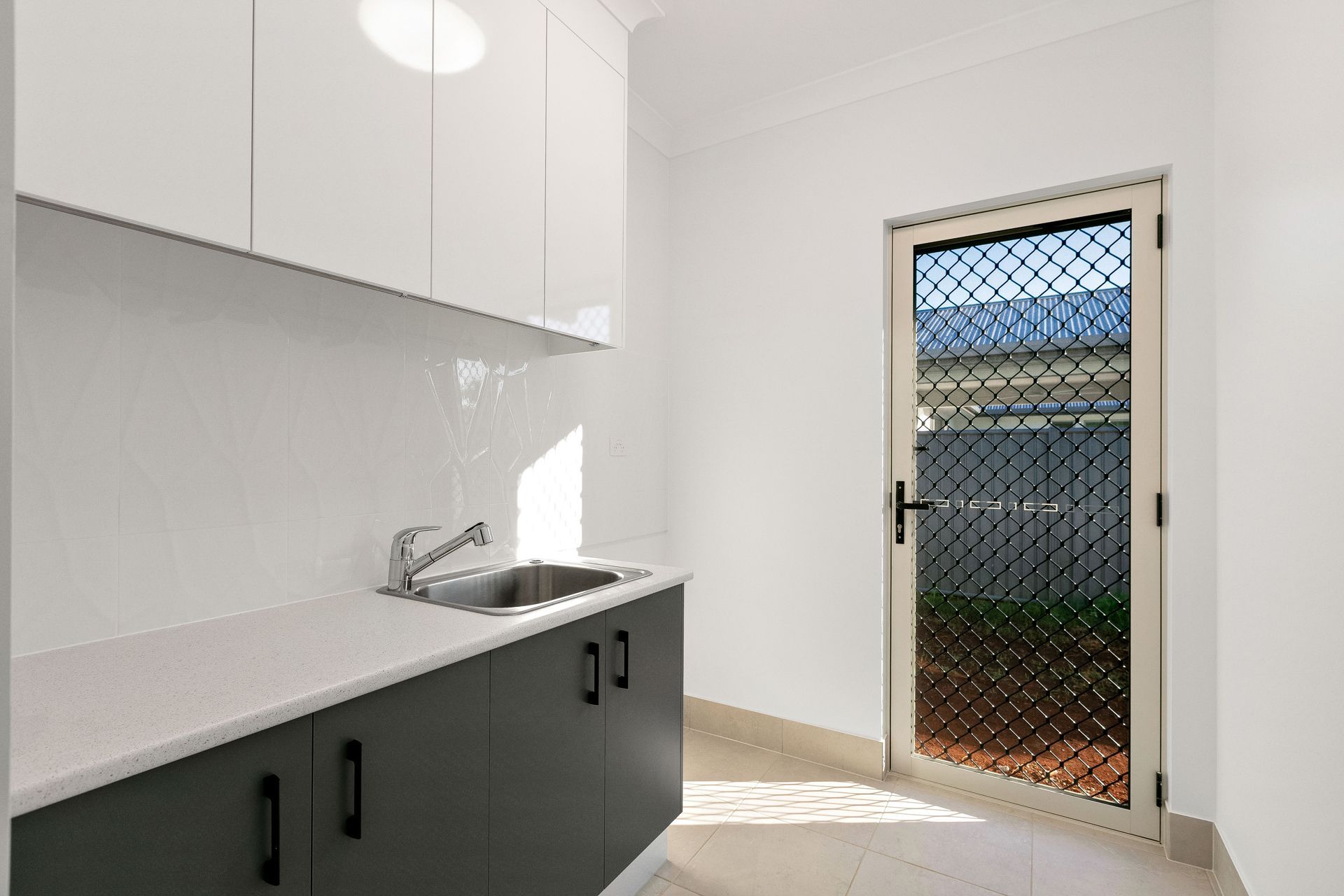 A Modern Laundry Room With White Upper Cabinets — Ashlee Jones Homes in Gordonvale, QLD