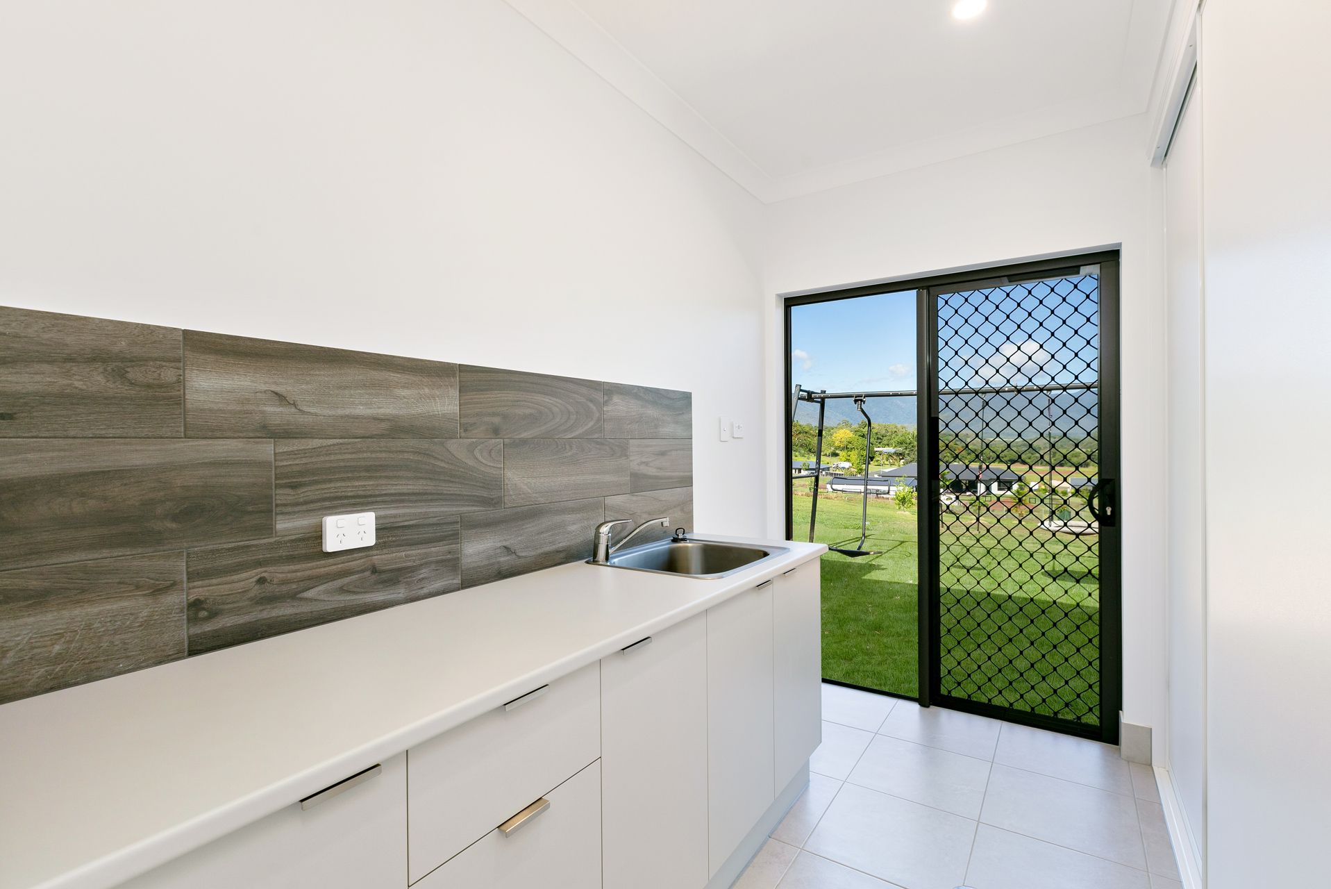 A Kitchen Area With Grey Wood-look Tiled Backsplash — Ashlee Jones Homes in Gordonvale, QLD