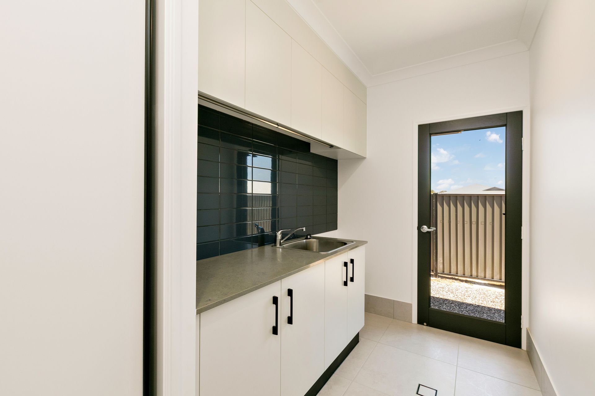 A Bright Laundry Room With White Cabinets — Ashlee Jones Homes in Gordonvale, QLD