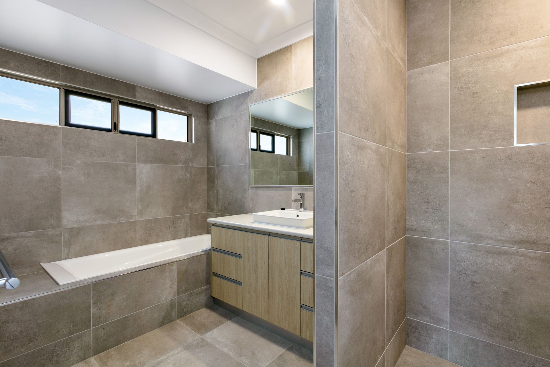 Modern Bathroom With Grey Stone Tiling, a Light Wood Vanity — Ashlee Jones Homes in Gordonvale, QLD