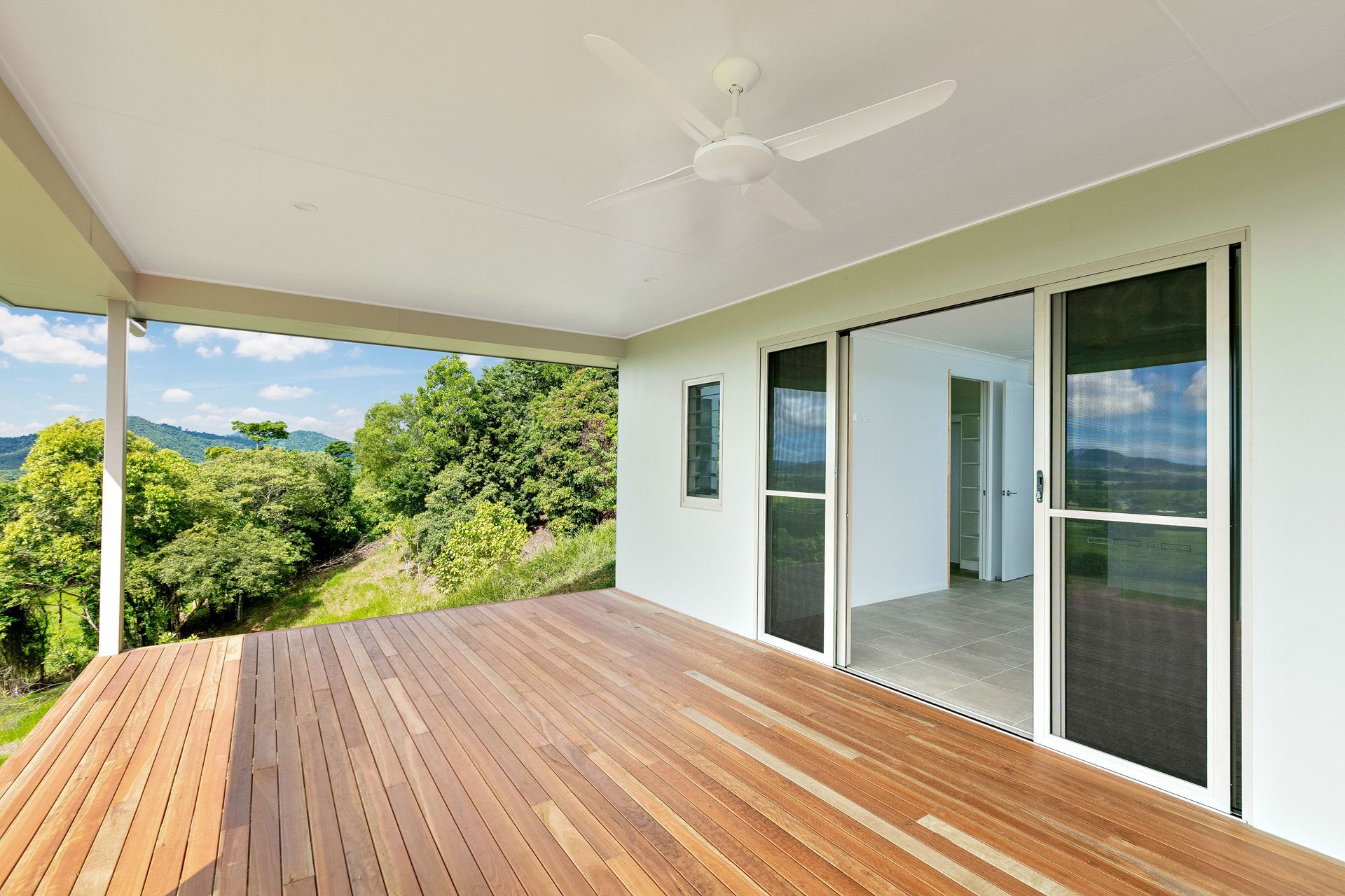 A Modern Covered Wooden Deck With a Ceiling Fan — Ashlee Jones Homes in Gordonvale, QLD