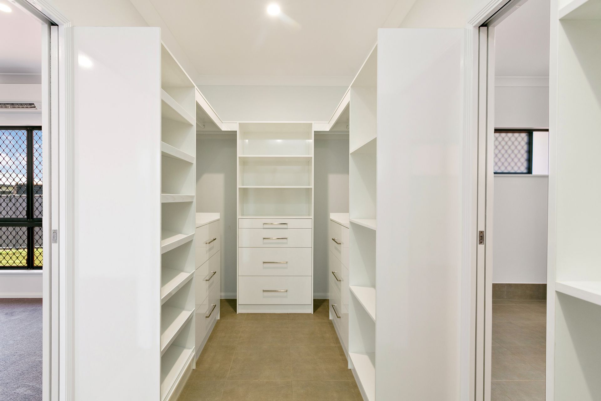 A Walk-in Closet Featuring White Shelves and Drawers — Ashlee Jones Homes in Gordonvale, QLD