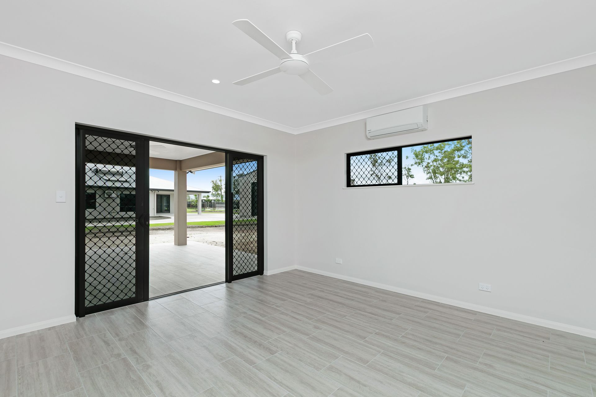 A Bright, Modern, Unfurnished Room With Light Wood Flooring, a Ceiling Fan — Ashlee Jones Homes in Gordonvale, QLD