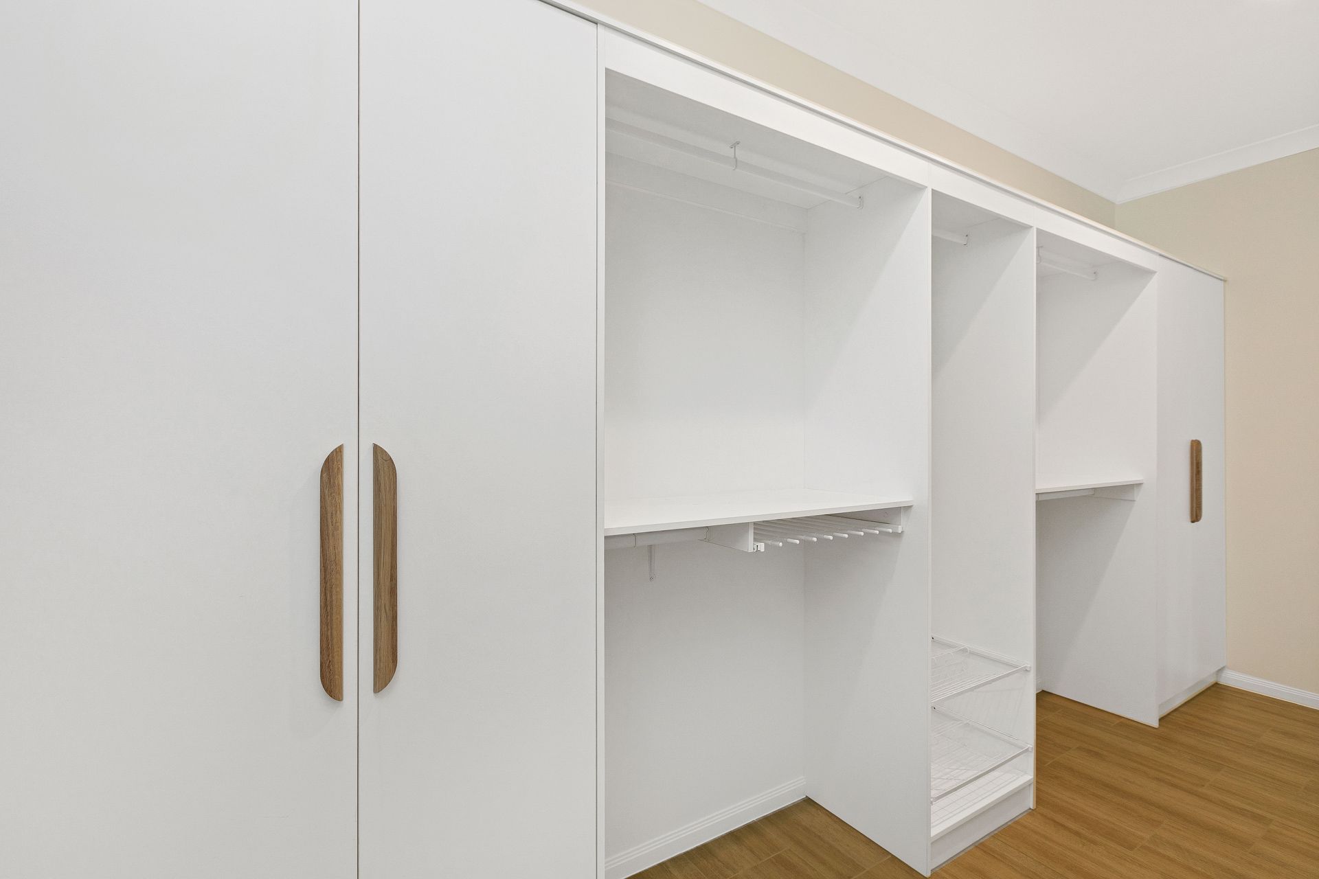 A White Closet Unit With Long, Vertical Wooden Handles — Ashlee Jones Homes in Gordonvale, QLD