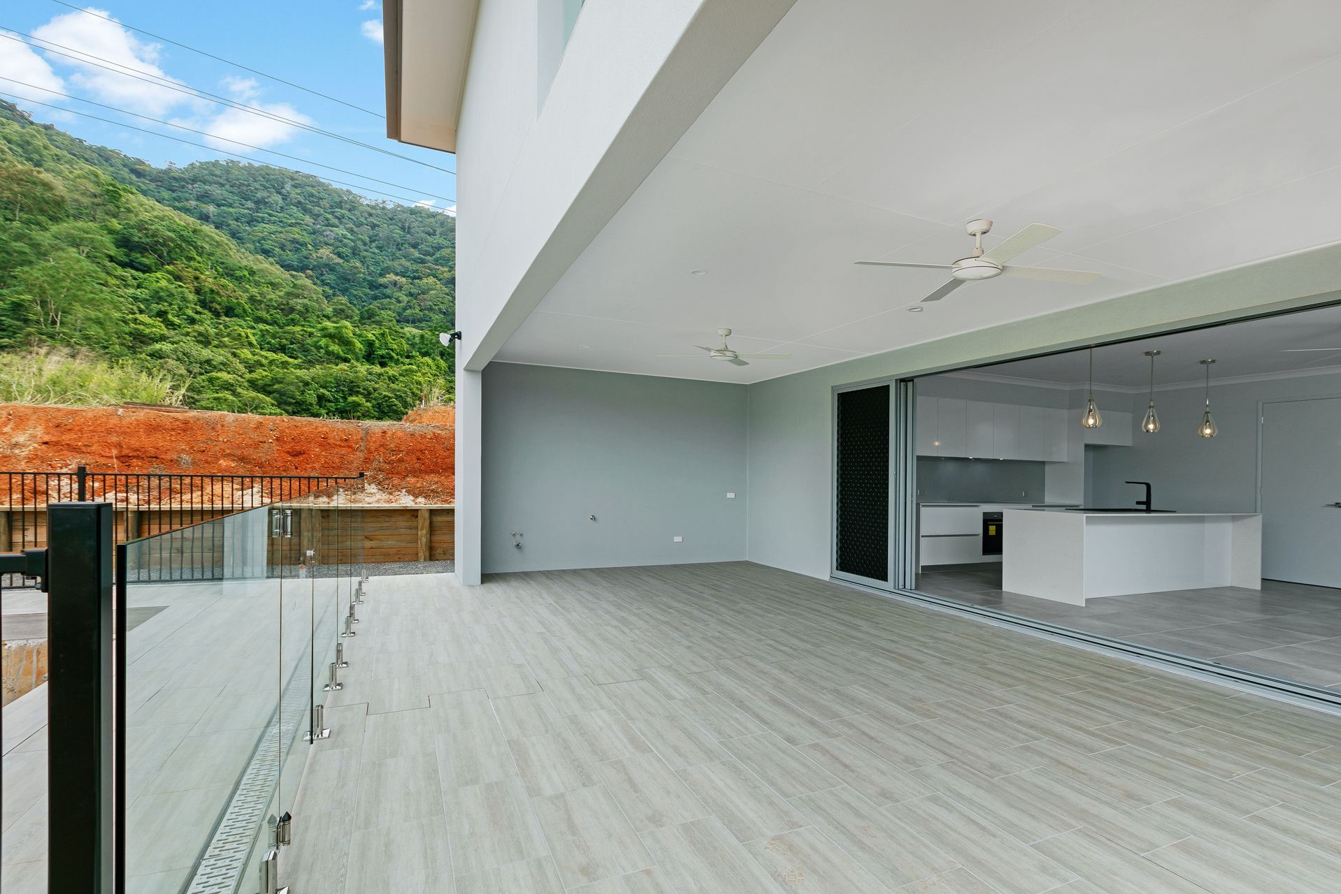 A Modern, Open-plan Patio With Wood-look Flooring and a Glass Railing — Ashlee Jones Homes in Gordonvale, QLD