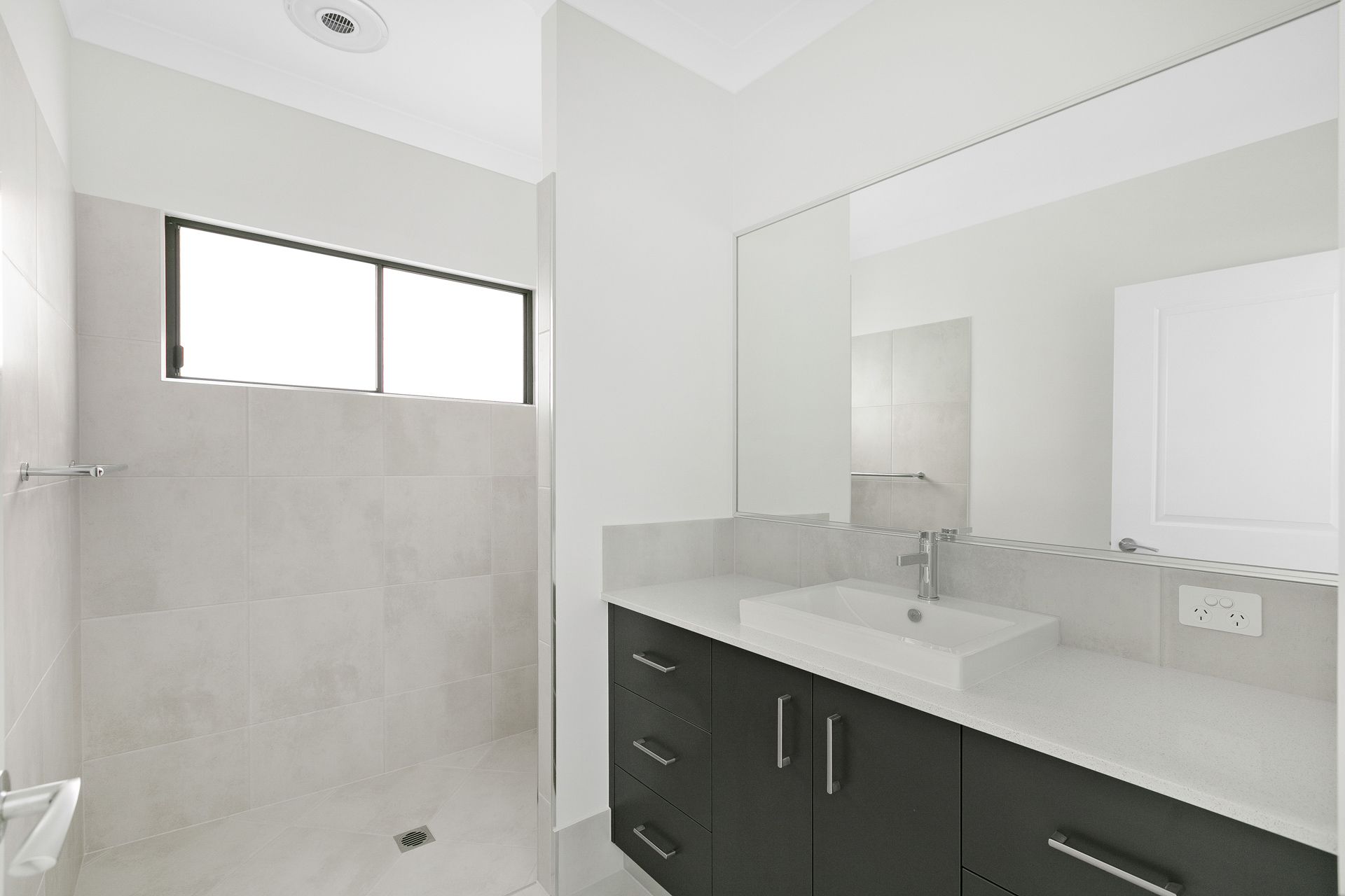 Modern Bathroom With a Dark Vanity, White Countertop — Ashlee Jones Homes in Gordonvale, QLD