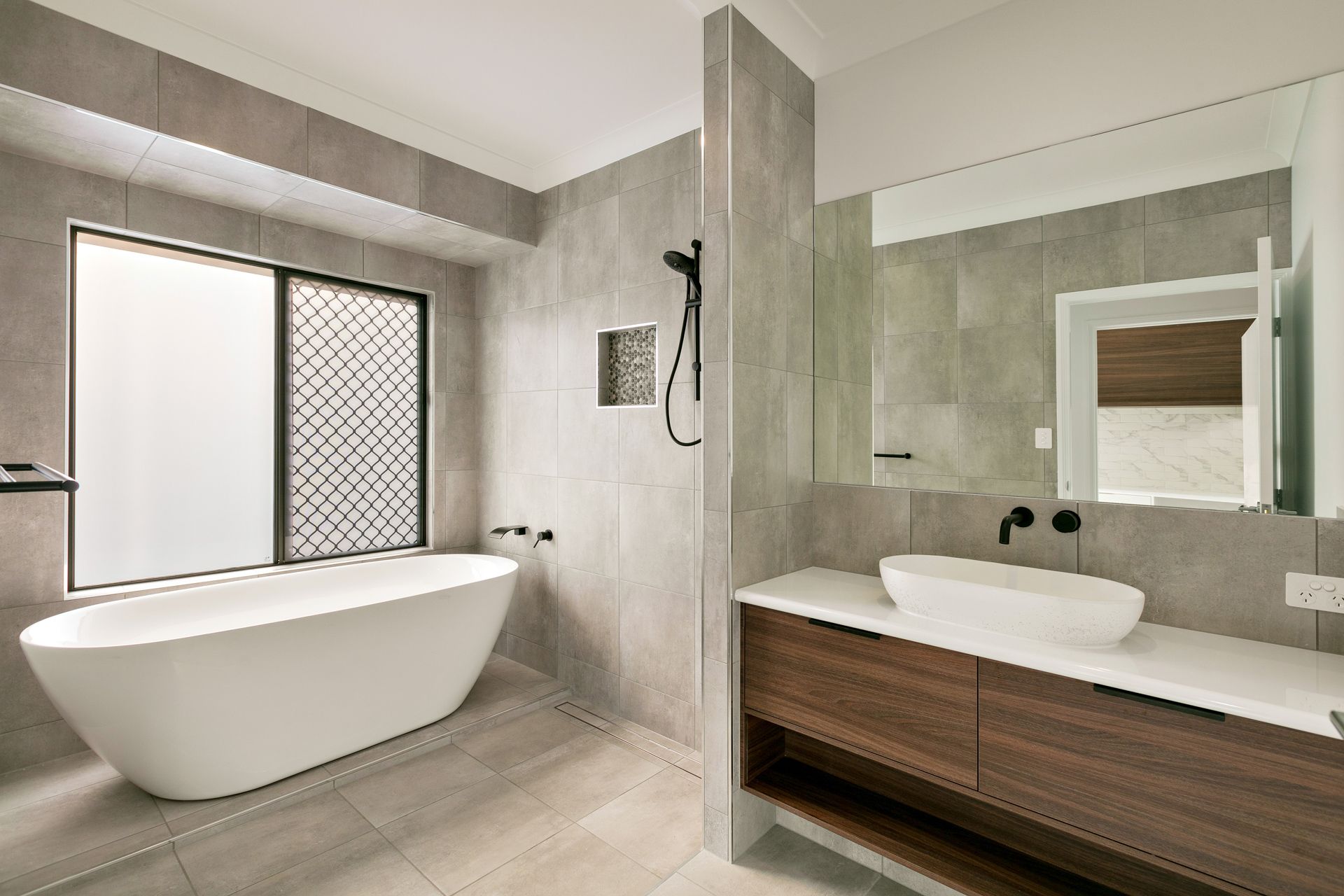 A Modern Bathroom Featuring a White Freestanding Bathtub — Ashlee Jones Homes in Gordonvale, QLD