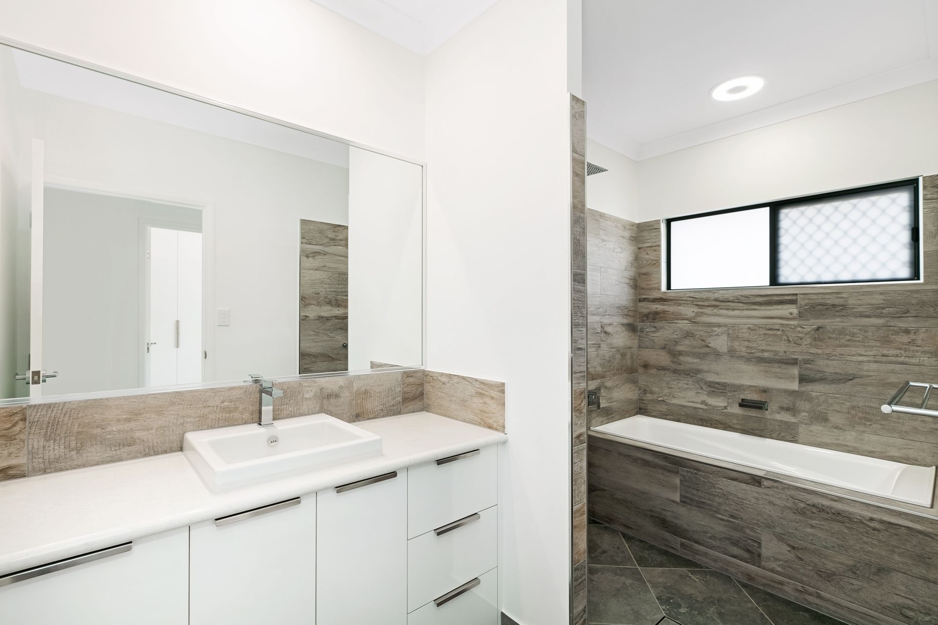 A Modern Bathroom With White Vanity Cabinets — Ashlee Jones Homes in Gordonvale, QLD