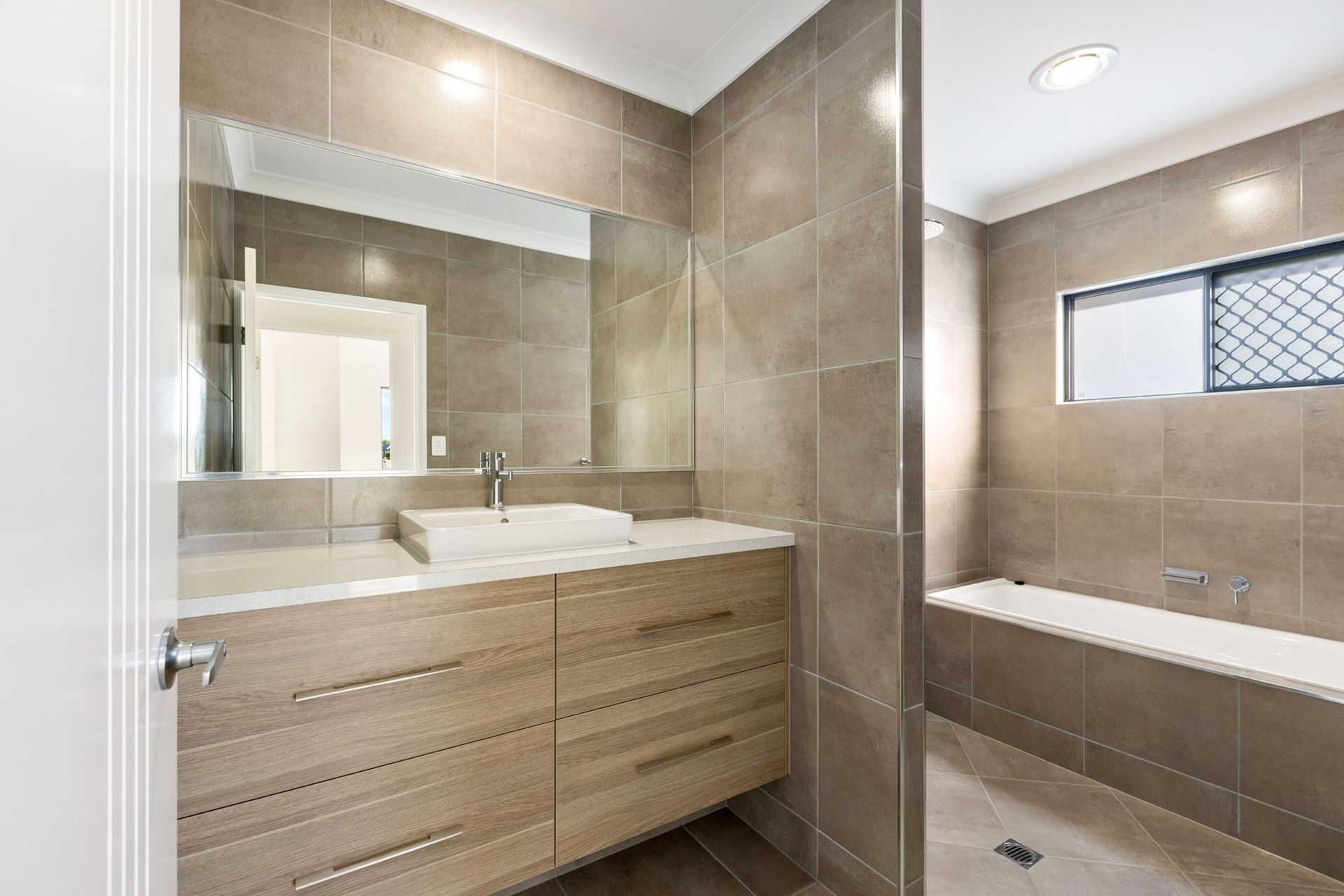 A Modern Bathroom With a Light Wood Vanity — Ashlee Jones Homes in Gordonvale, QLD