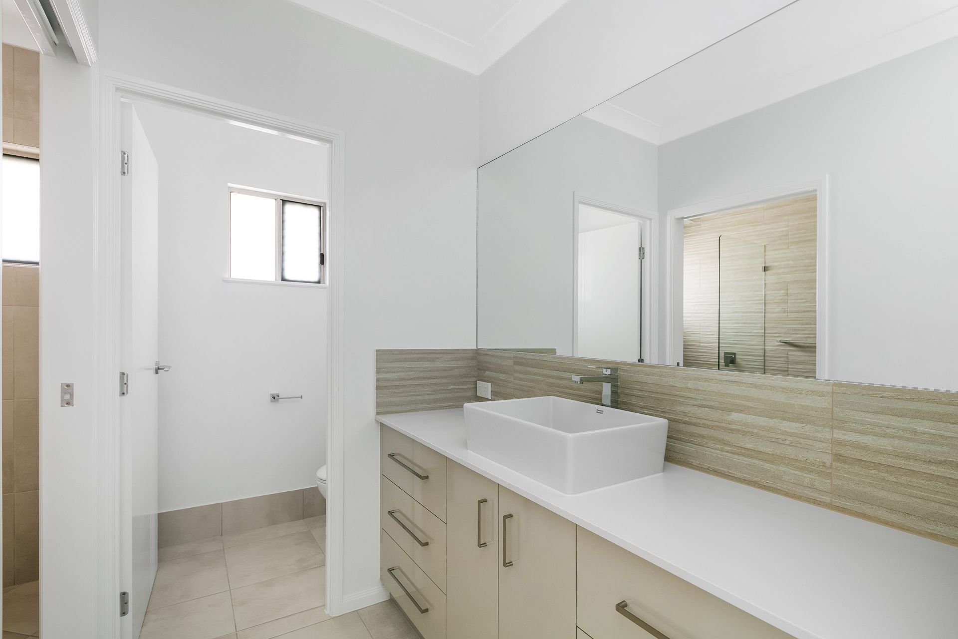 A Modern Bathroom Featuring a White Rectangular Sink on a Beige Cabinet — Ashlee Jones Homes in Gordonvale, QLD