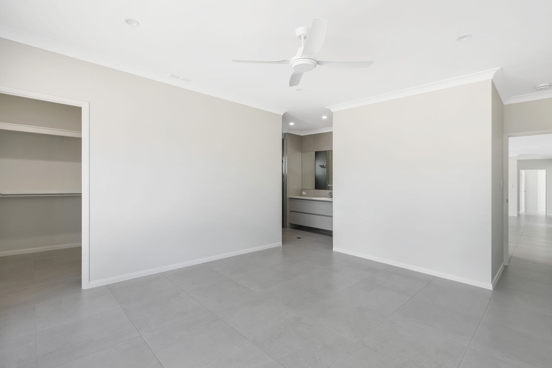 An Empty, Modern Room With Light Gray Walls and Tile Flooring — Ashlee Jones Homes in Gordonvale, QLD
