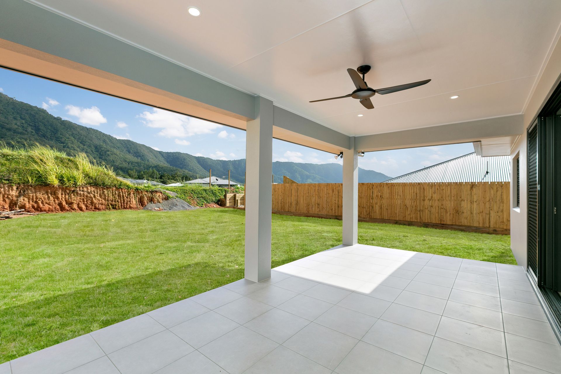 A Covered Patio With Light Grey Tiles Overlooks a Green Lawn — Ashlee Jones Homes in Gordonvale, QLD