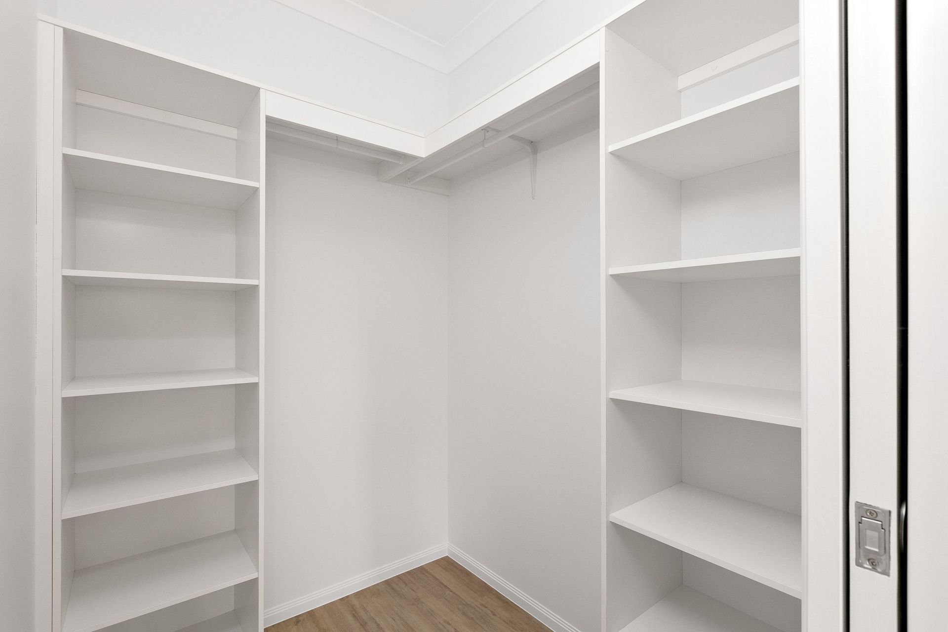 An Empty, L-shaped Walk-in Closet With White Wooden Shelving Units — Ashlee Jones Homes in Gordonvale, QLD