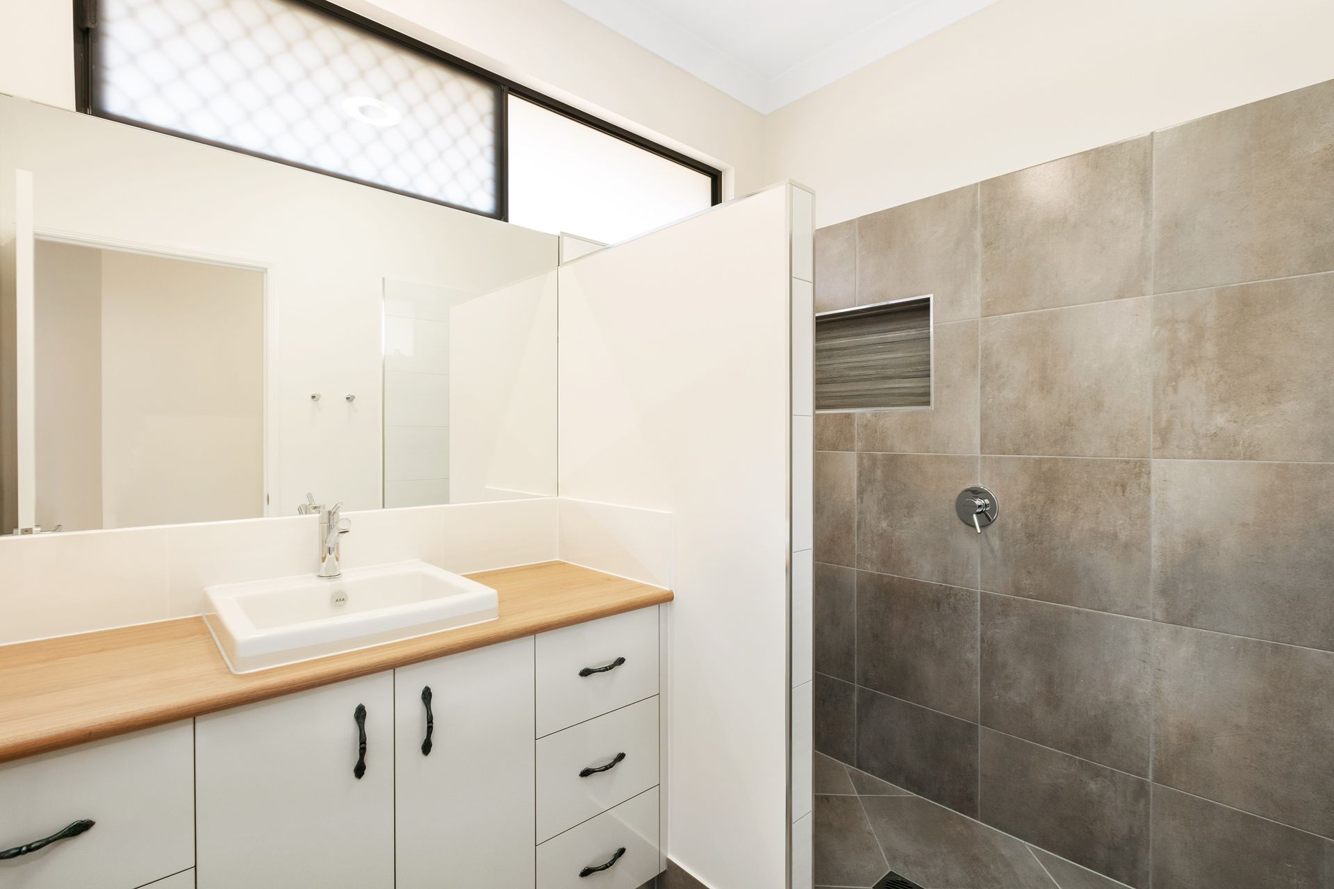 A Modern Bathroom Featuring a White Vanity With a Wooden Countertop — Ashlee Jones Homes in Gordonvale, QLD