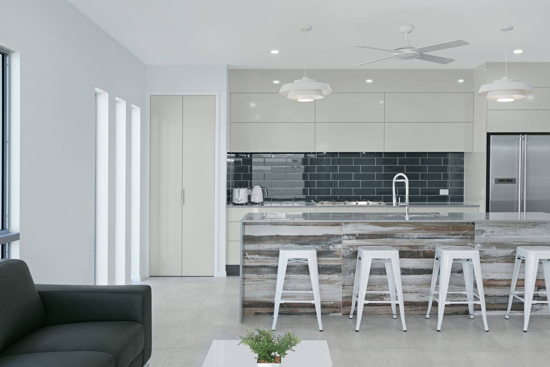 A Modern Kitchen With White Cabinetry, a Weathered Wood-paneled Island — Ashlee Jones Homes in Gordonvale, QLD