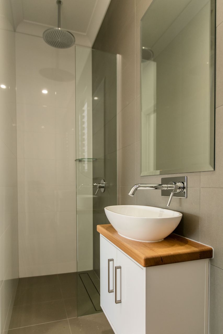 A Modern Bathroom Featuring a White Vessel Sink on a Wooden Vanity — Ashlee Jones Homes in Gordonvale, QLD