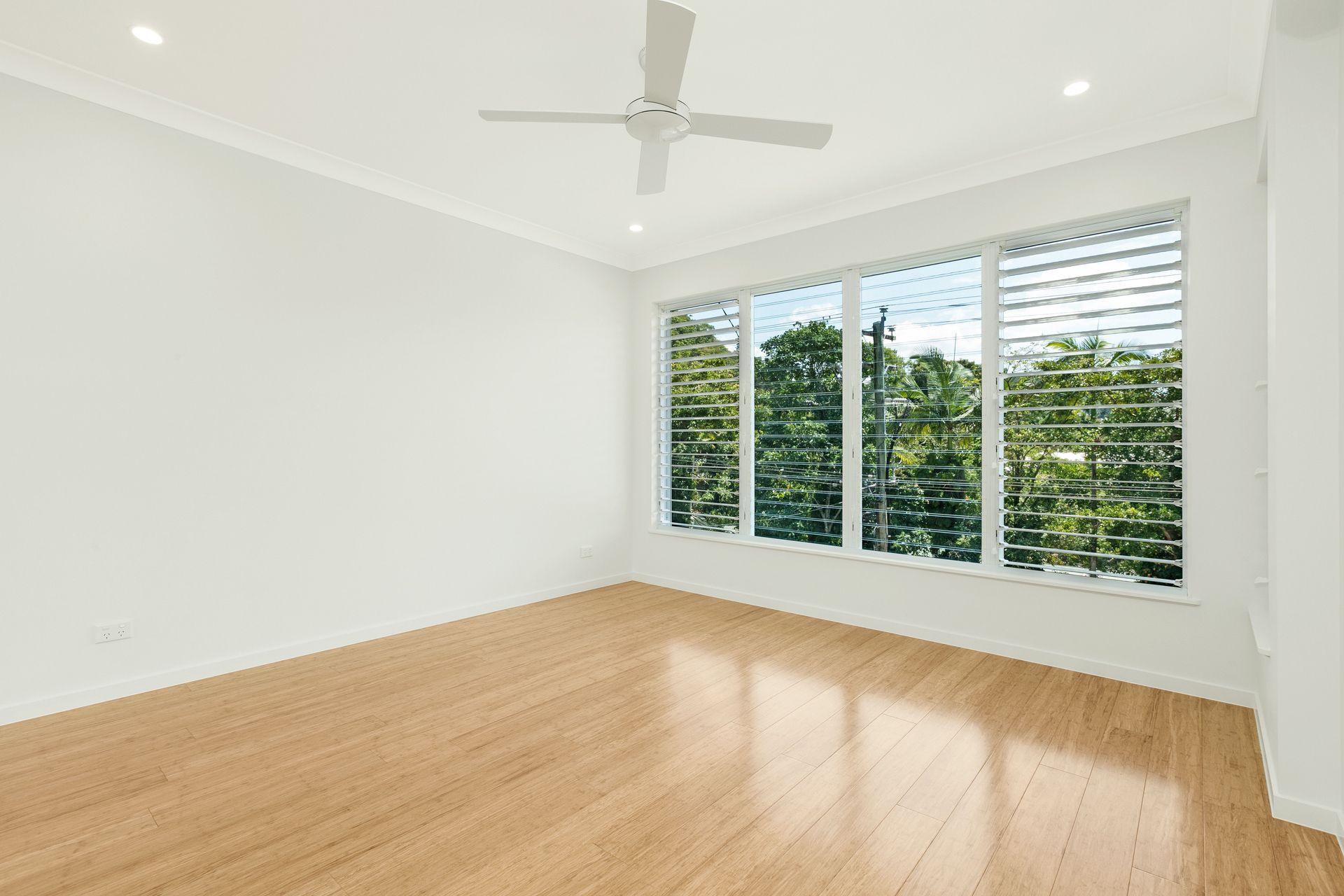 A Bright, Empty Room With Light Wood Flooring, White Walls — Ashlee Jones Homes in Gordonvale, QLD