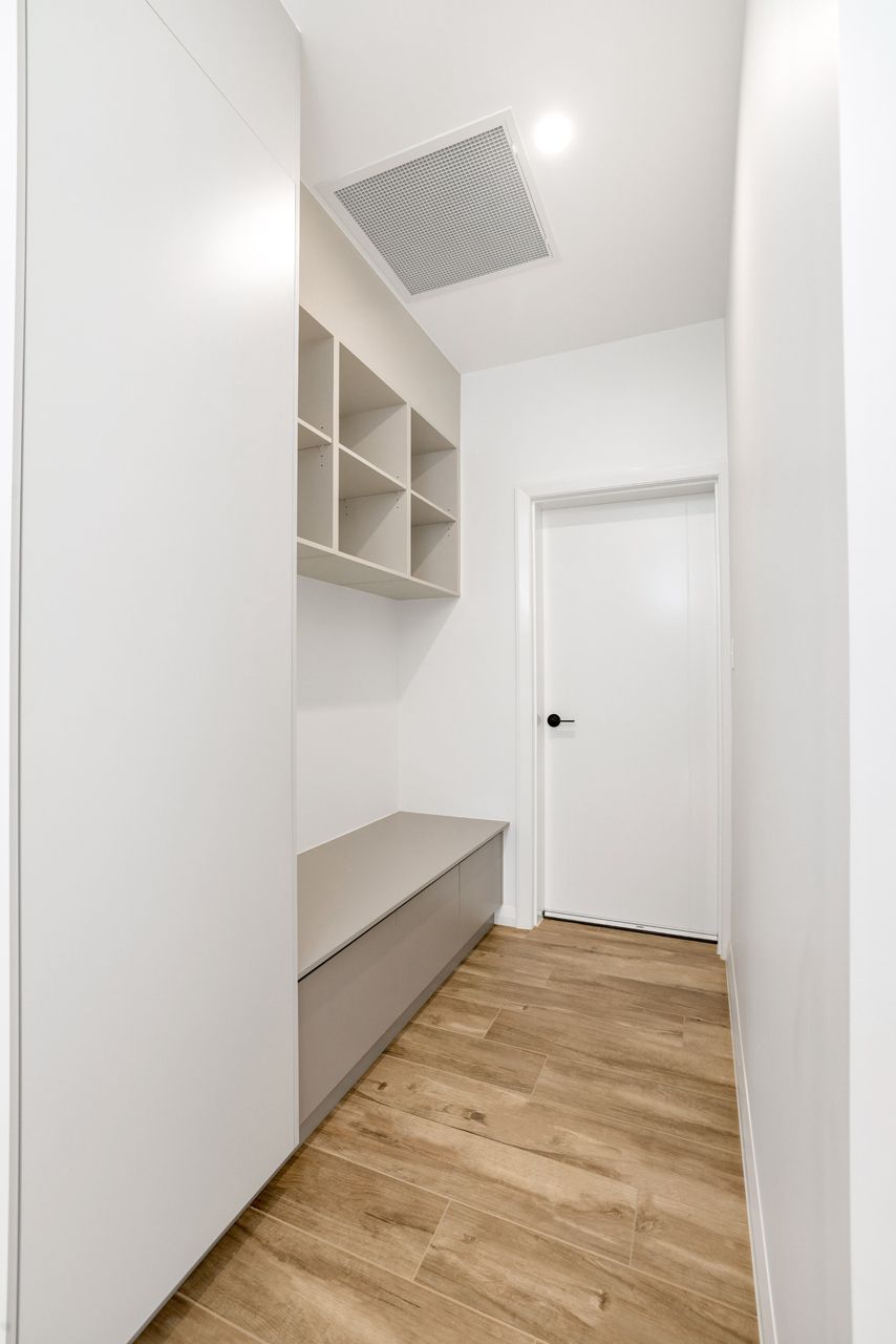 A Hallway With Light Wood Flooring, Featuring a Built-in Beige Bench — Ashlee Jones Homes in Gordonvale, QLD