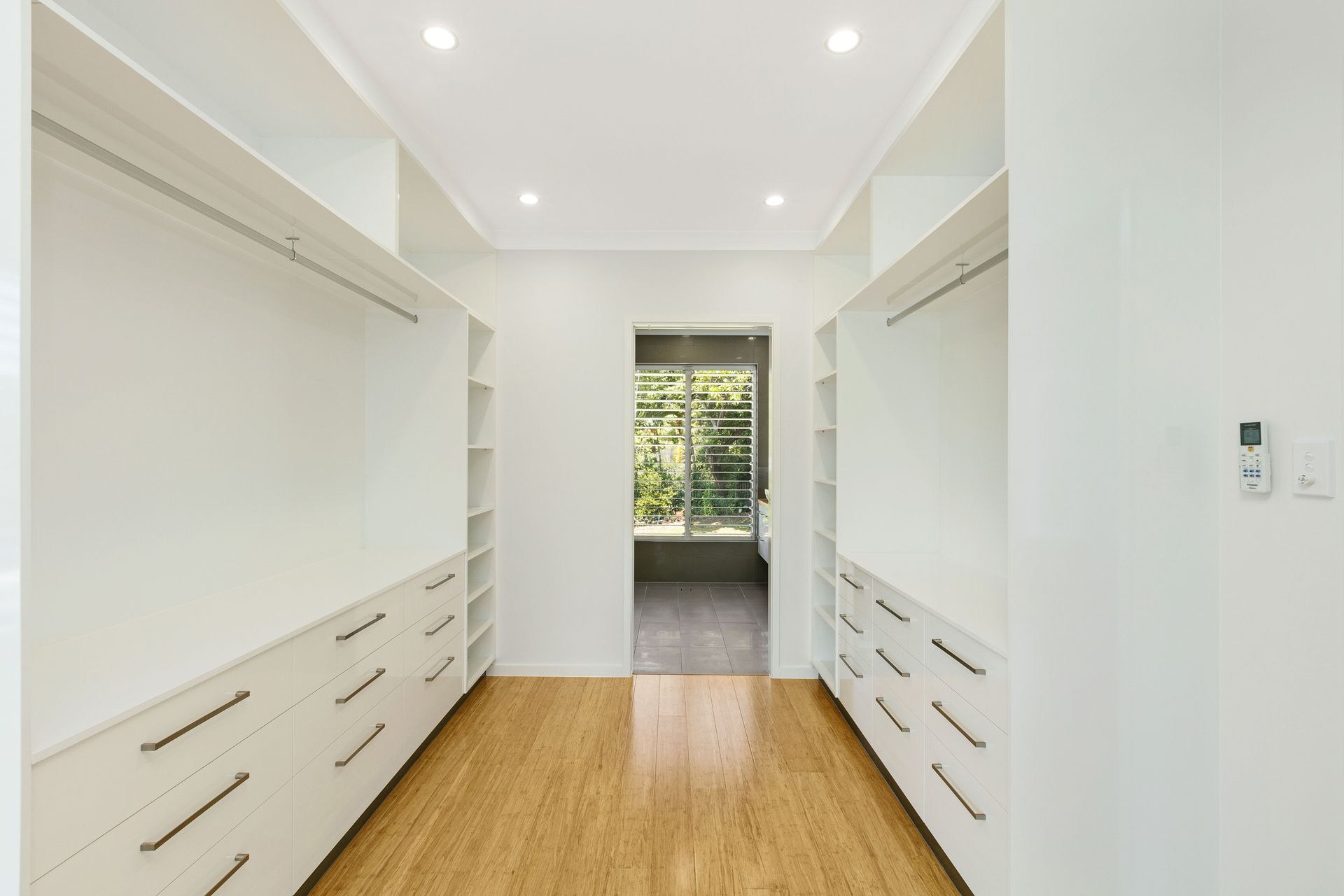 A Bright Walk-in Closet With White Custom Cabinetry — Ashlee Jones Homes in Gordonvale, QLD