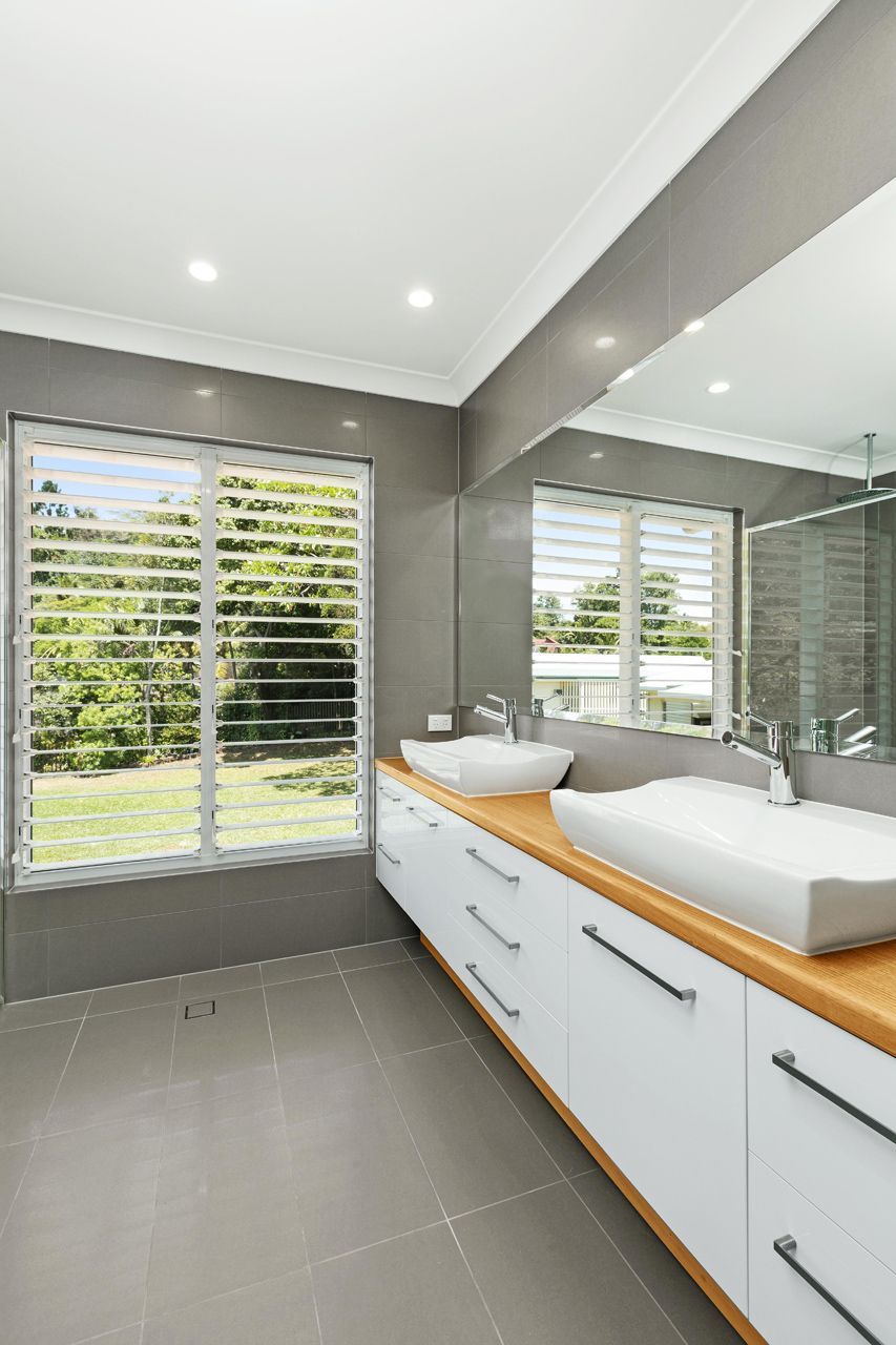 Modern Bathroom With Grey Tiled Walls, a Wooden Vanity — Ashlee Jones Homes in Gordonvale, QLD