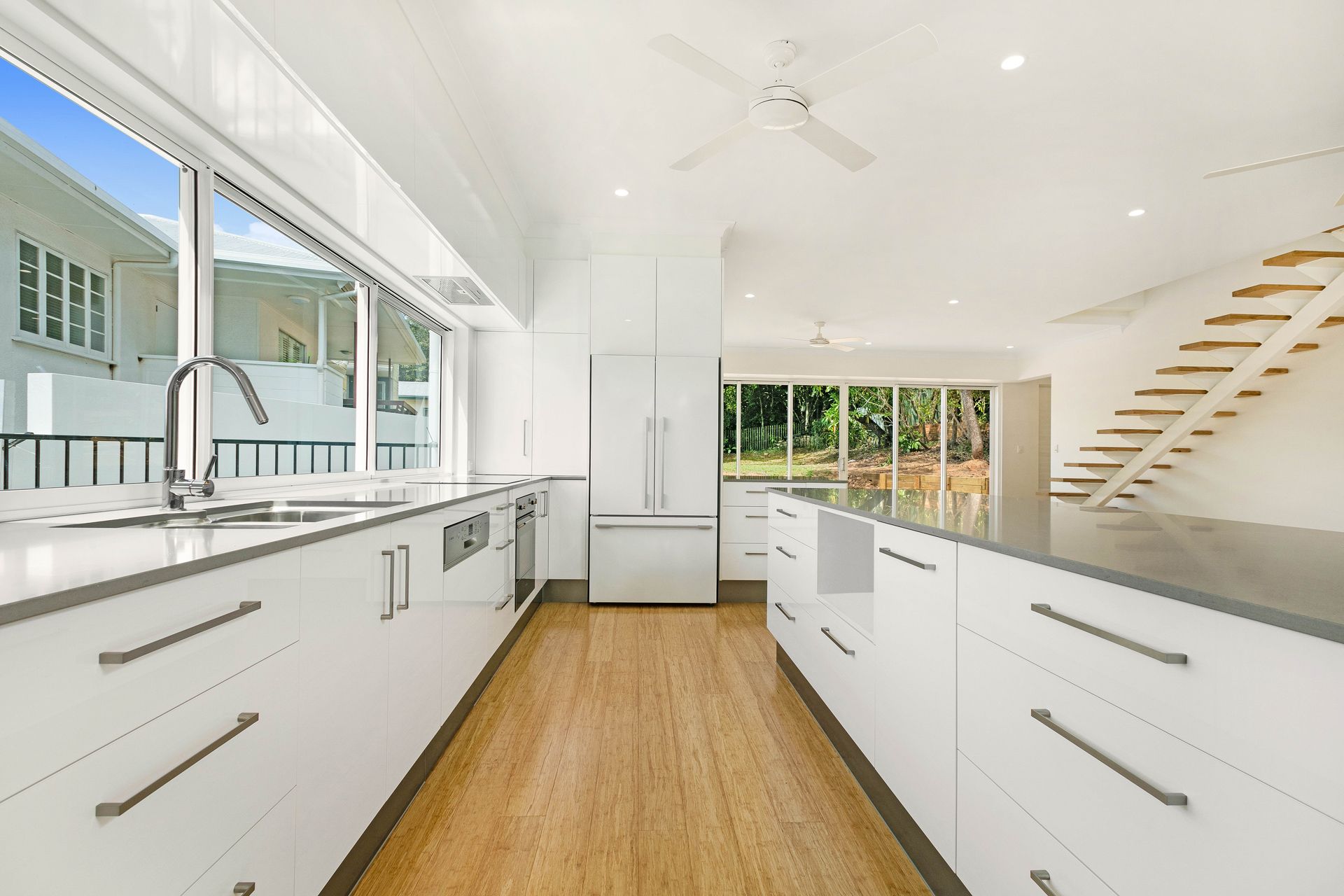 A Modern Kitchen With White Cabinetry, Light Wood Floors — Ashlee Jones Homes in Gordonvale, QLD